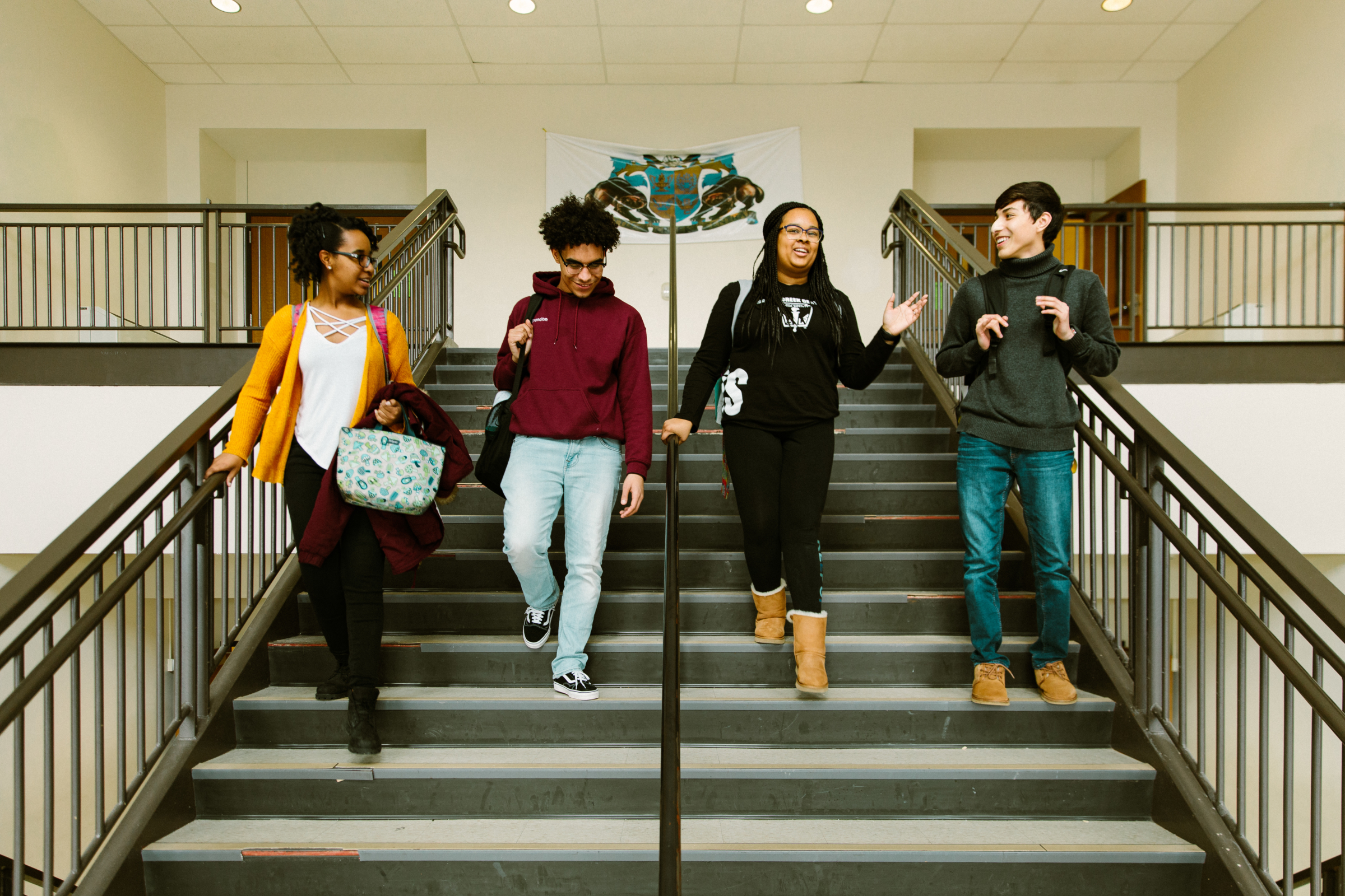 Four students talking while walking down stairs