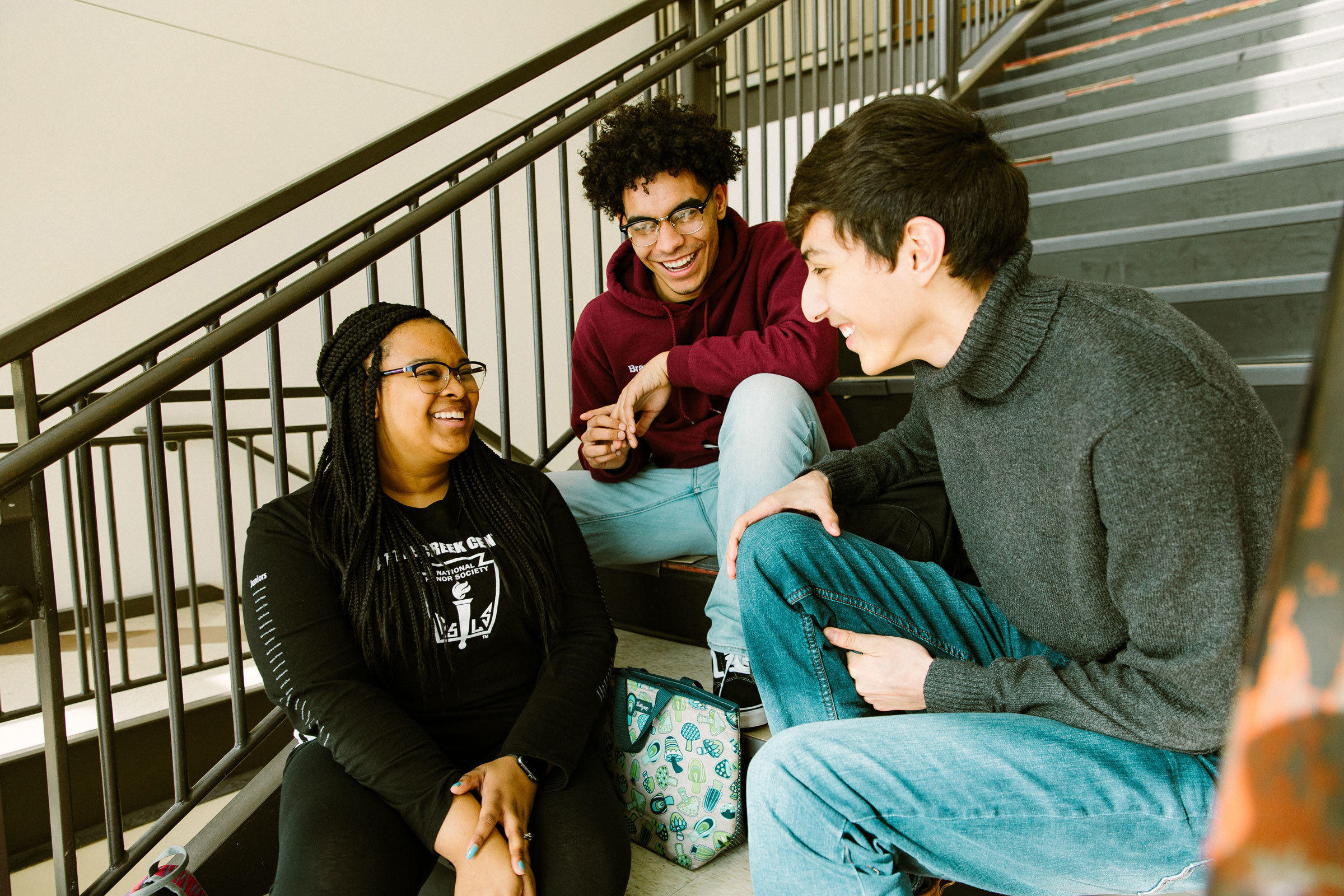 Three students engaged in conversation sitting on a stairwell