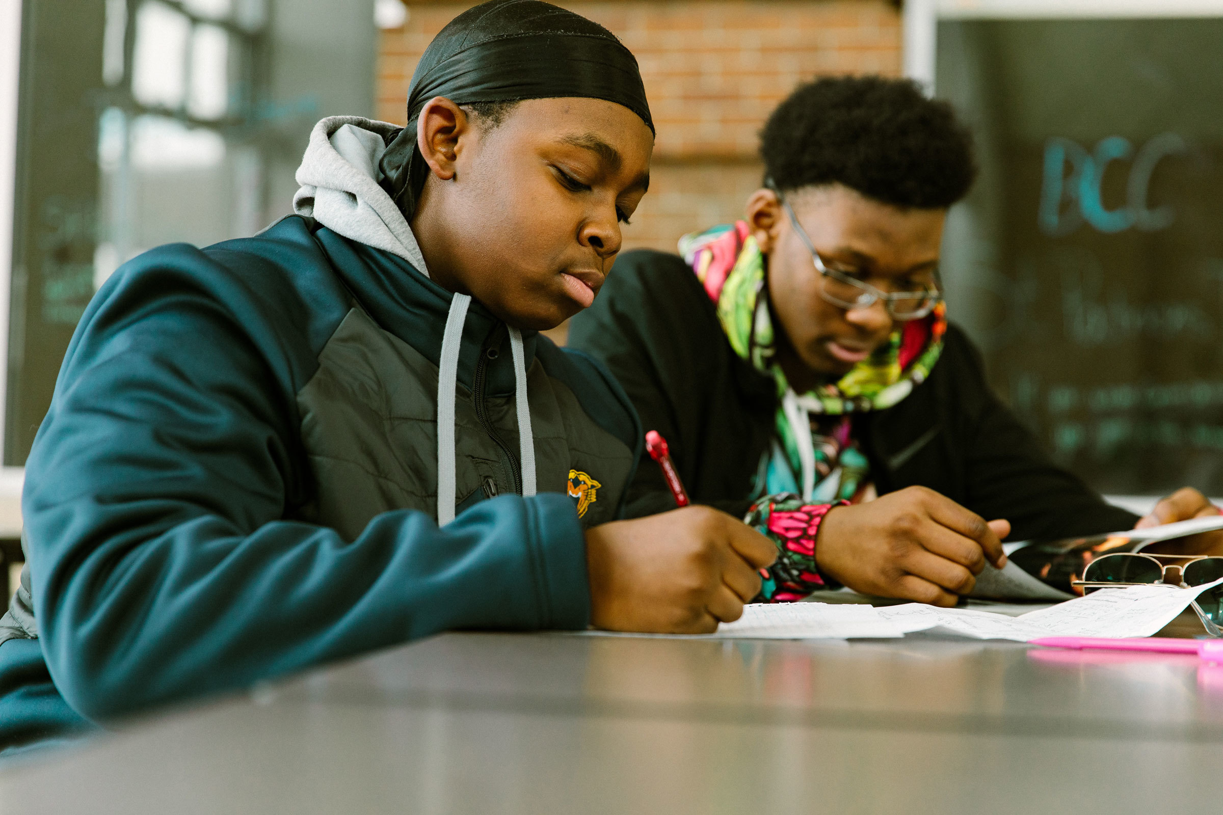 Two students studying and writing at a table