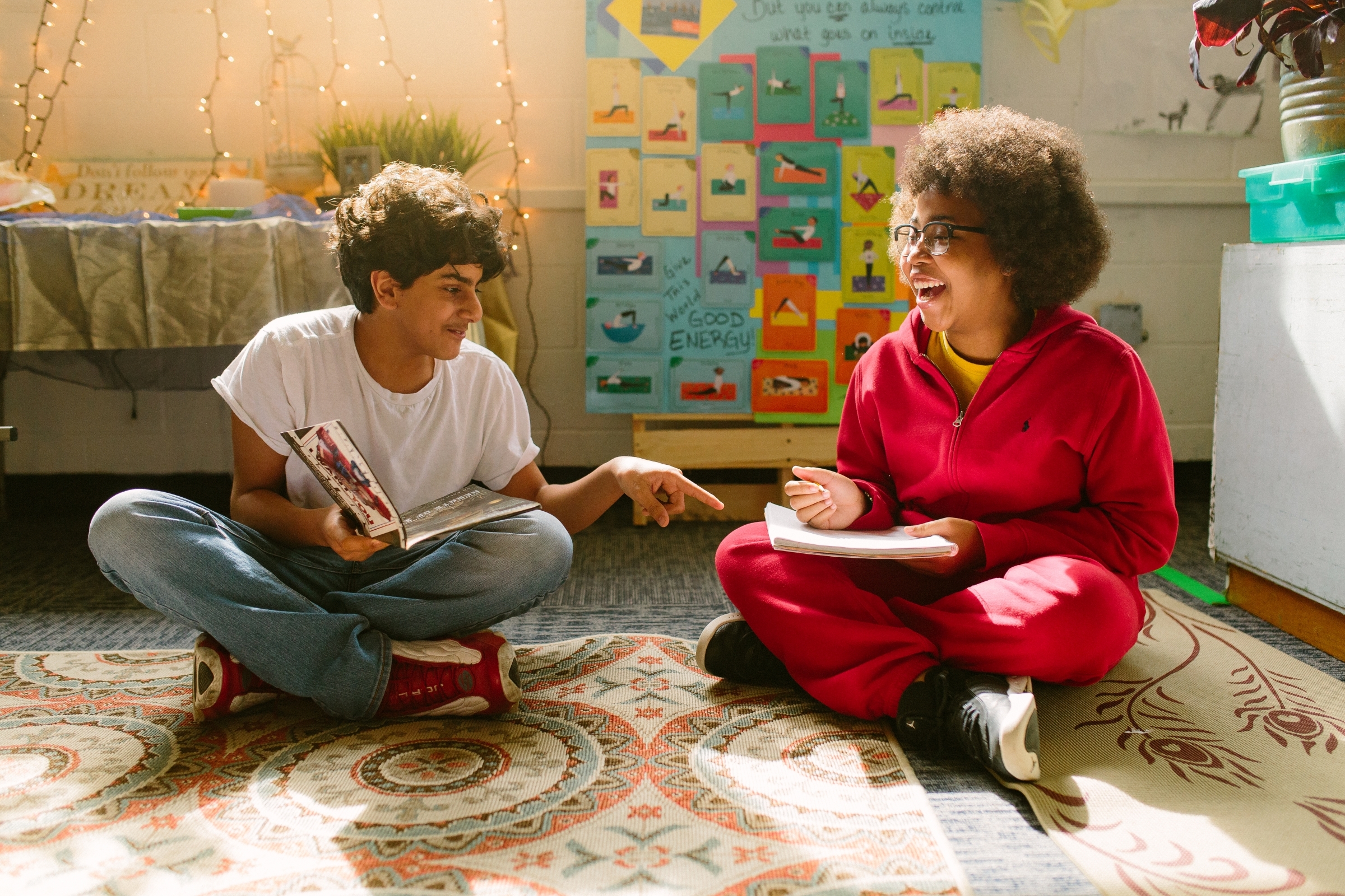 boy and girl sitting cross-legged reading and laughing
