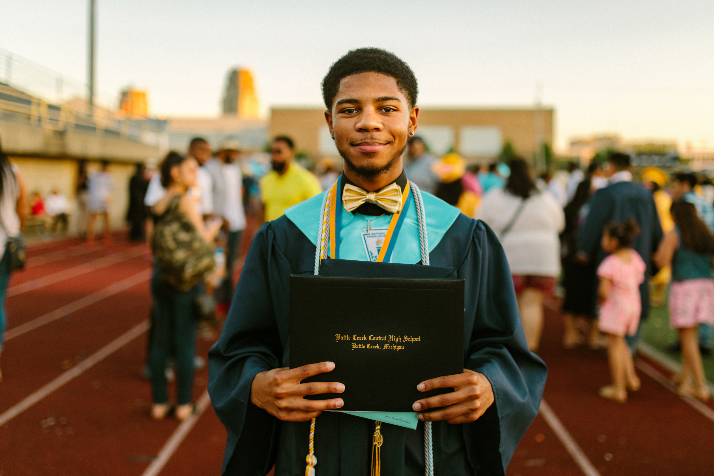 Student in a graduation gown holding a diploma after the high school ceremony.