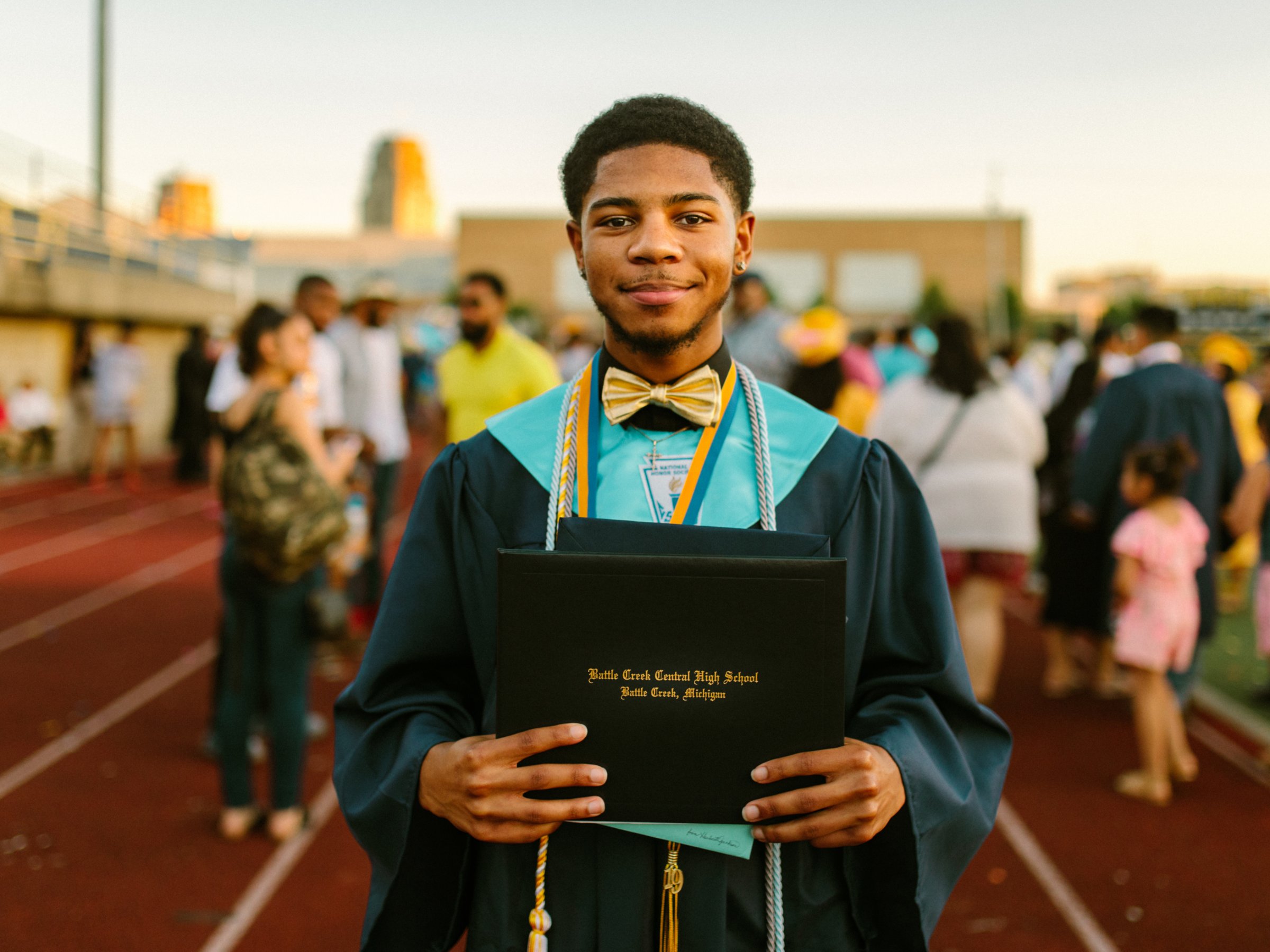 Student in a graduation gown holding a diploma after the high school ceremony.