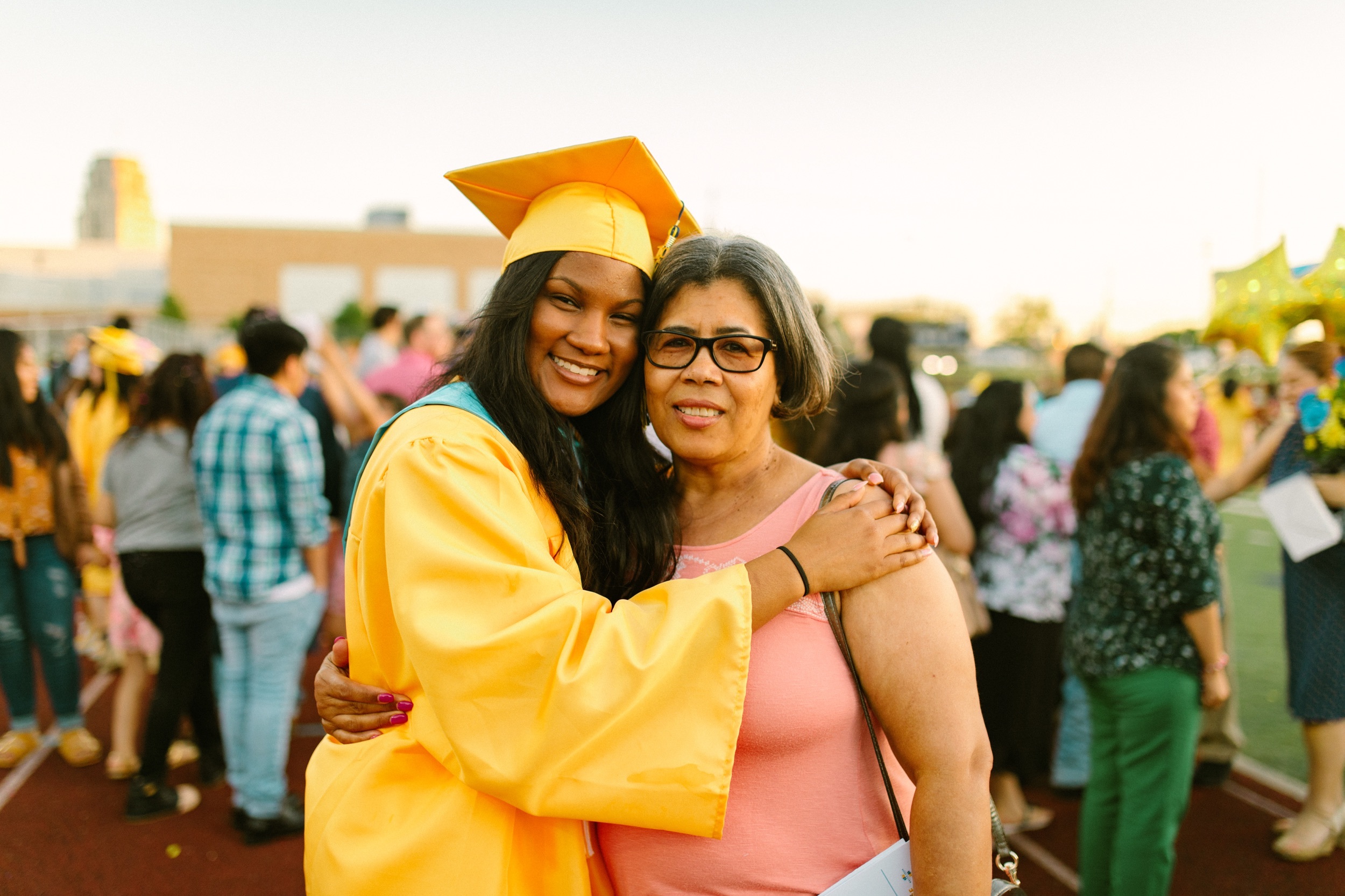 A graduating senior in cap and gown hugs a parent at the ceremony
