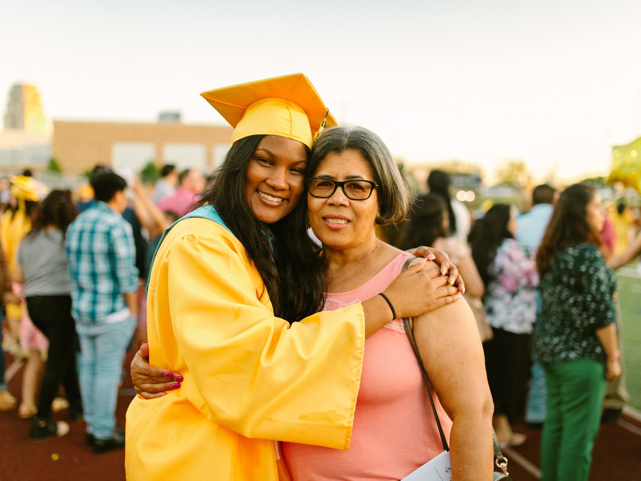 A graduating senior in cap and gown hugs a parent at the ceremony