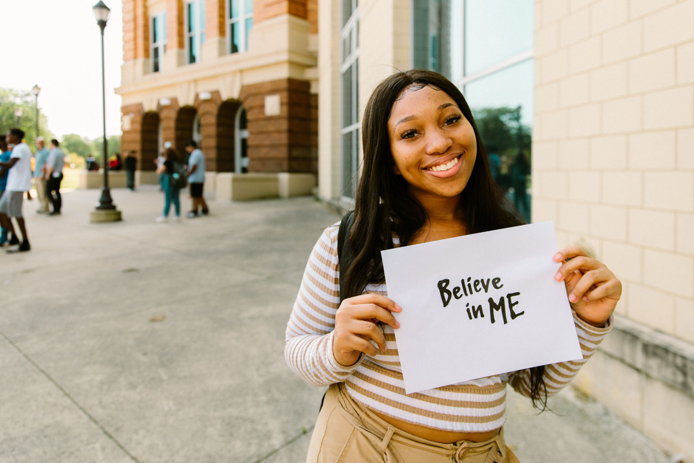 Girl smiling with believe in me sign