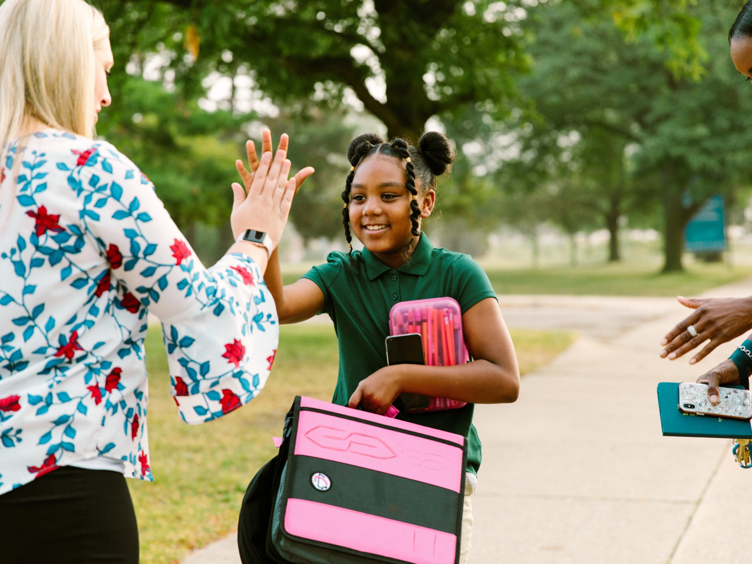 A teacher high-fives a student walking to school