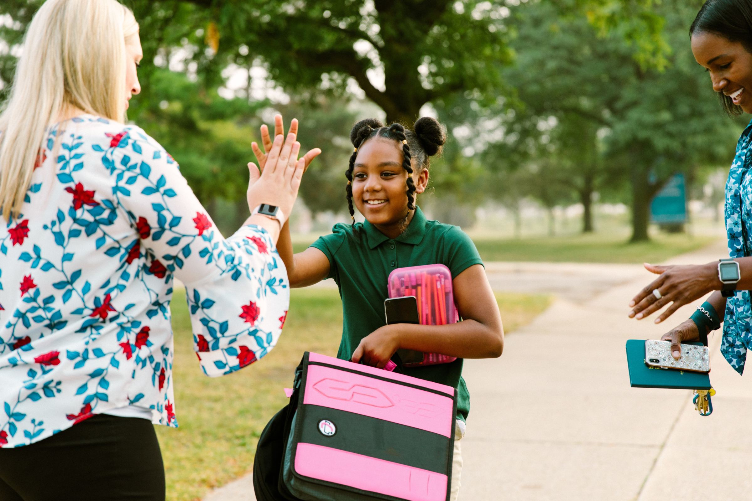 A teacher high-fives a student walking to school