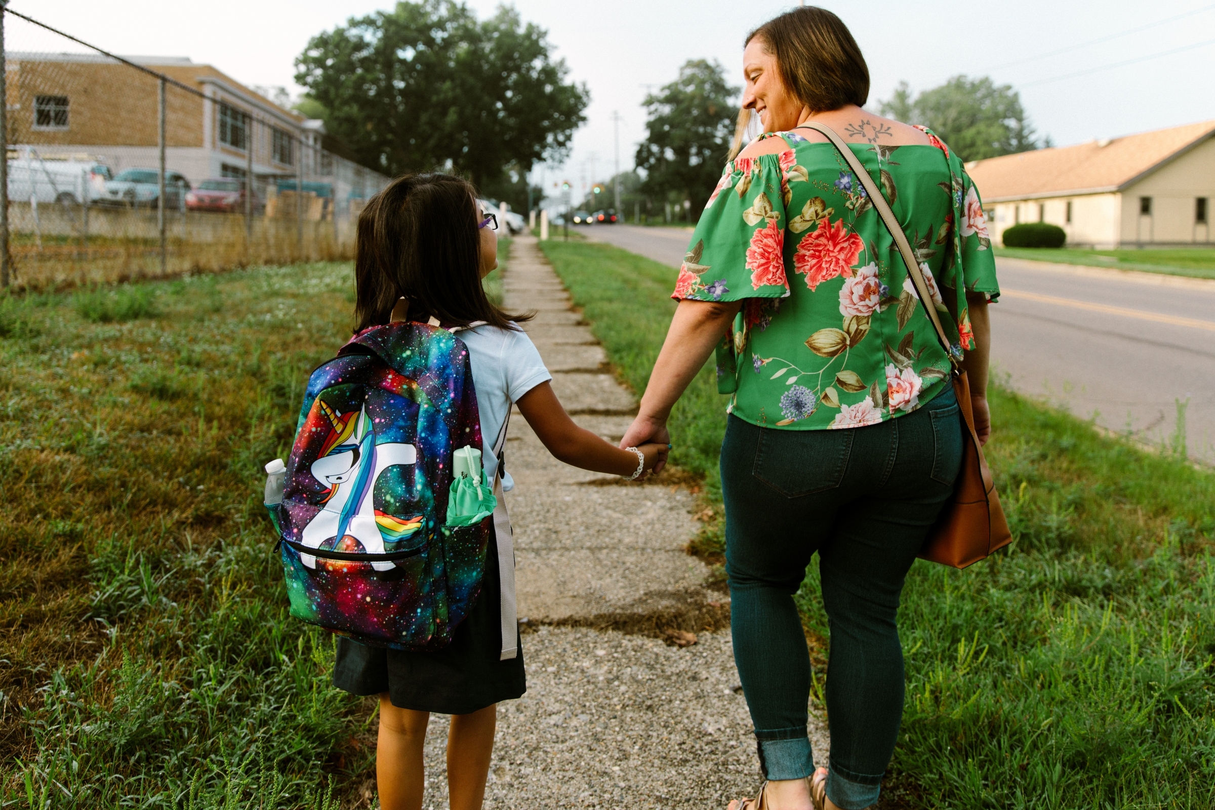 parent holding hands with daughter facing away from camera