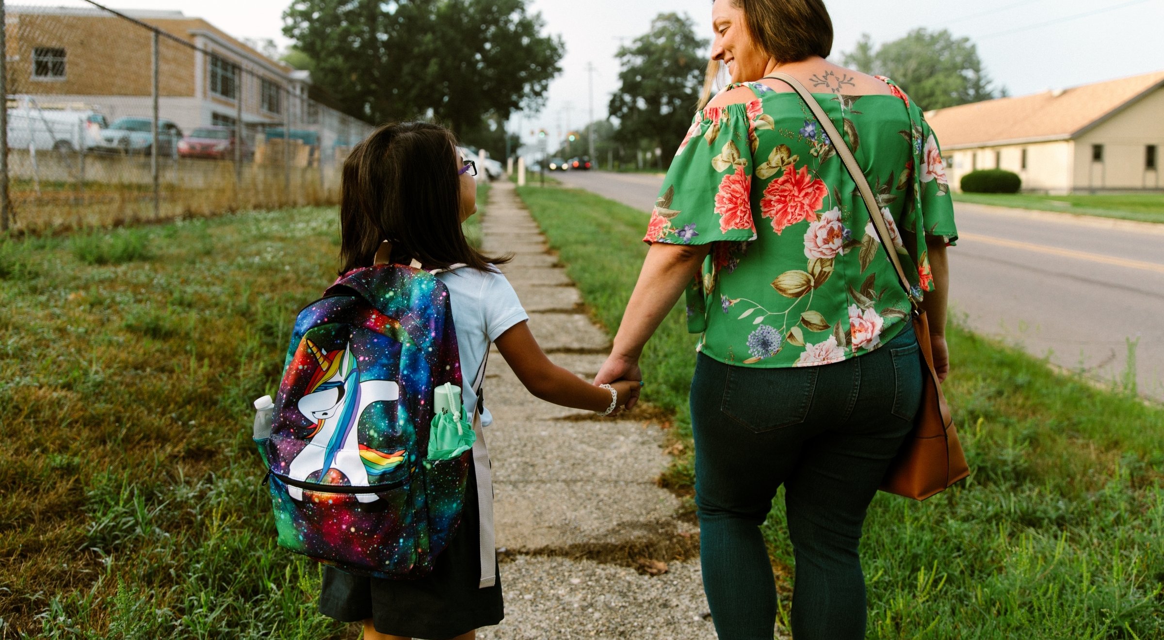 parent holding hands with daughter facing away from camera