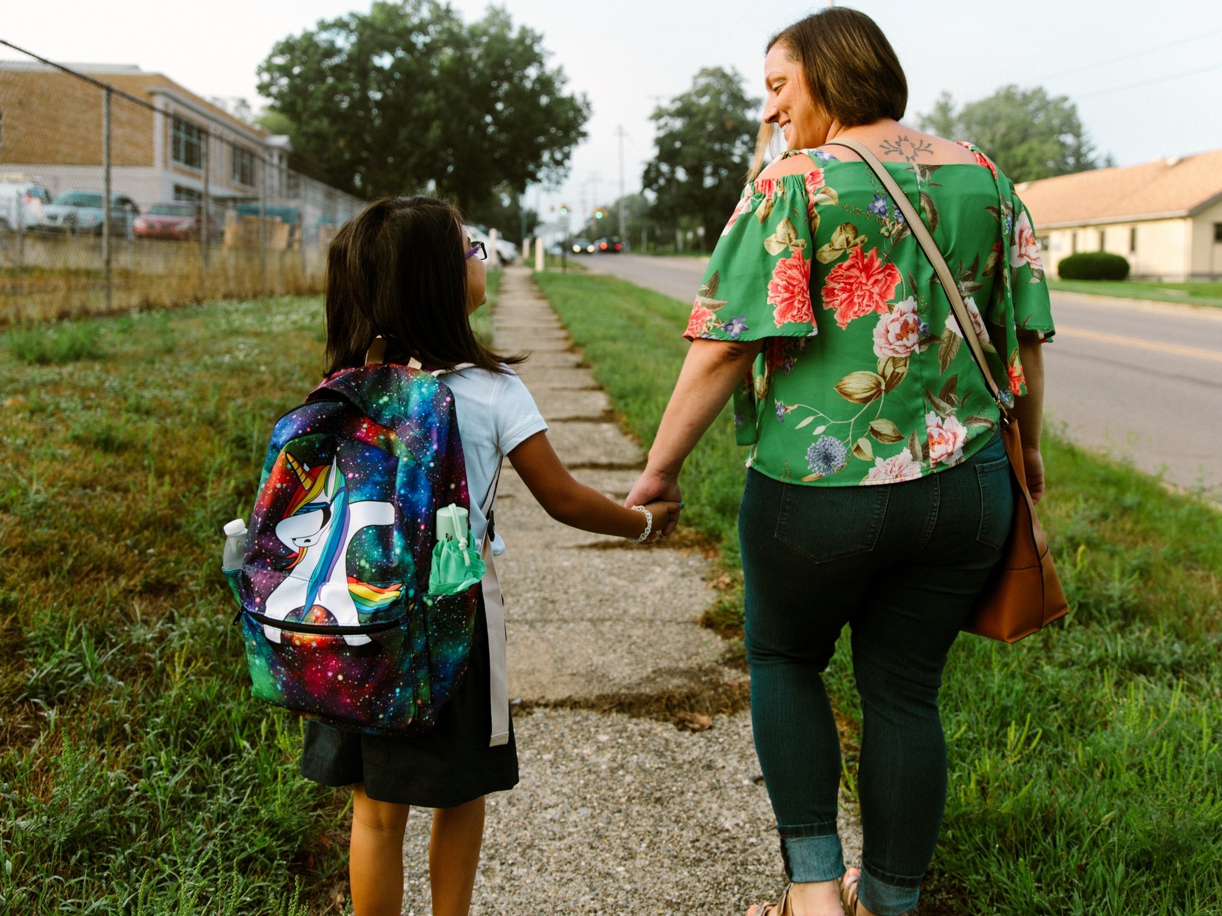 parent holding hands with daughter facing away from camera
