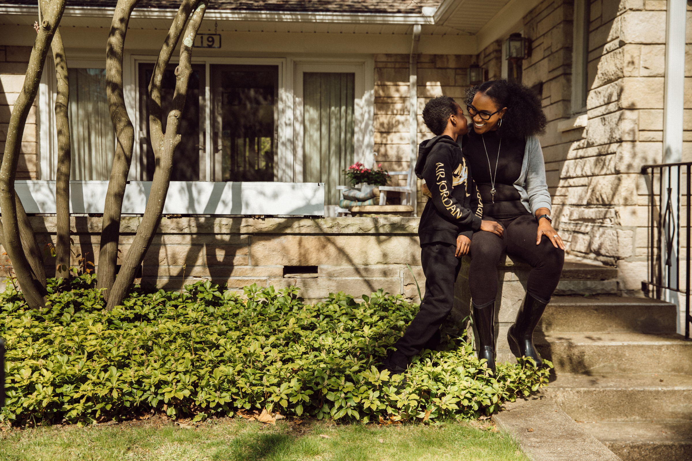 A mother and son sitting on their front porch, smiling.