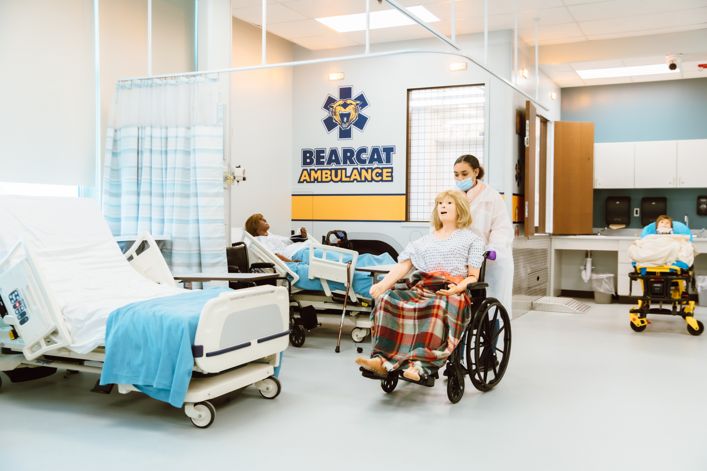 A BCCHS Career Academies student pushes a mannequin in a wheelchair inside the new Health Care Simulation Lab