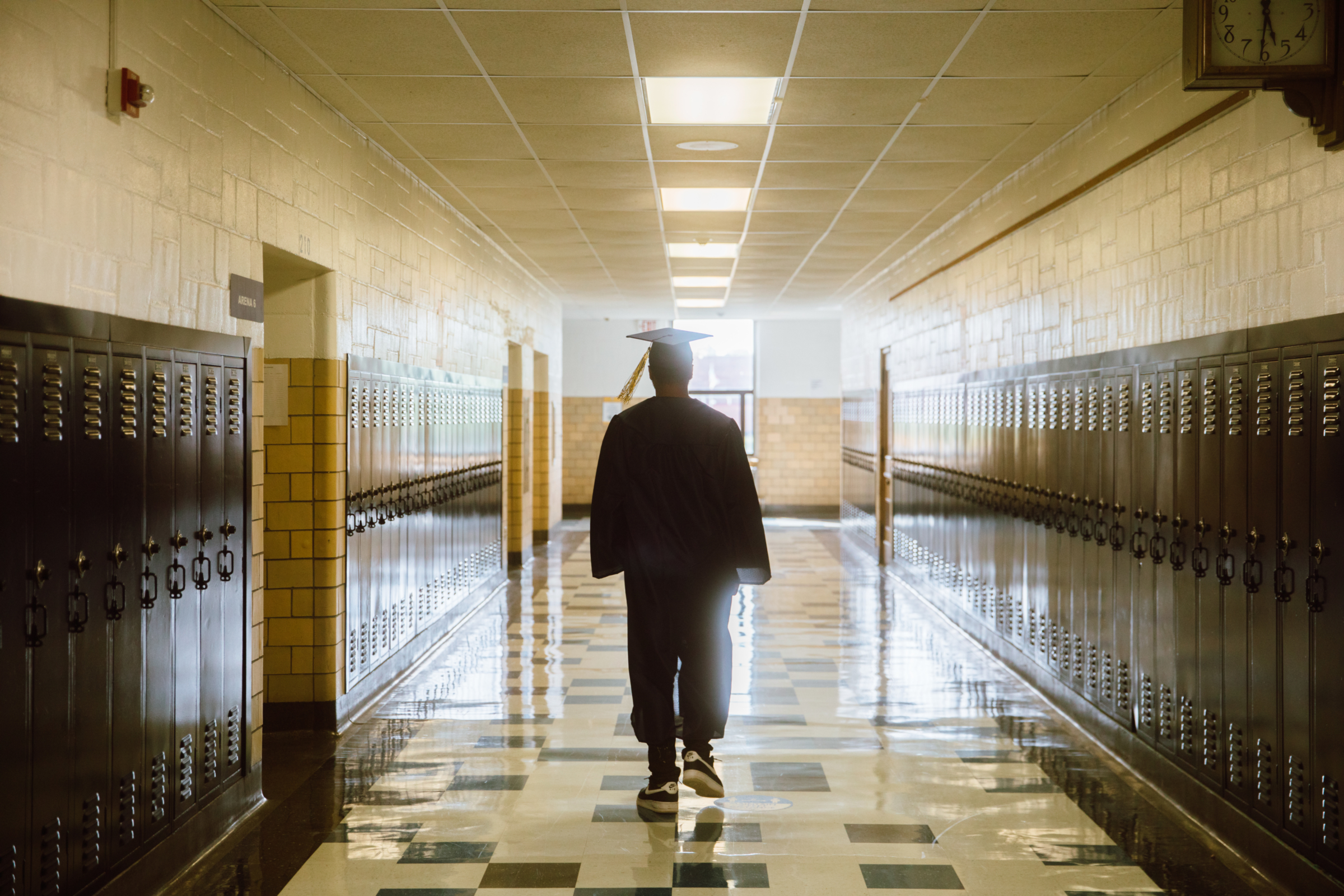 Student walking down the halls of WK Prep with a graduation wearing a graduation cap and gown