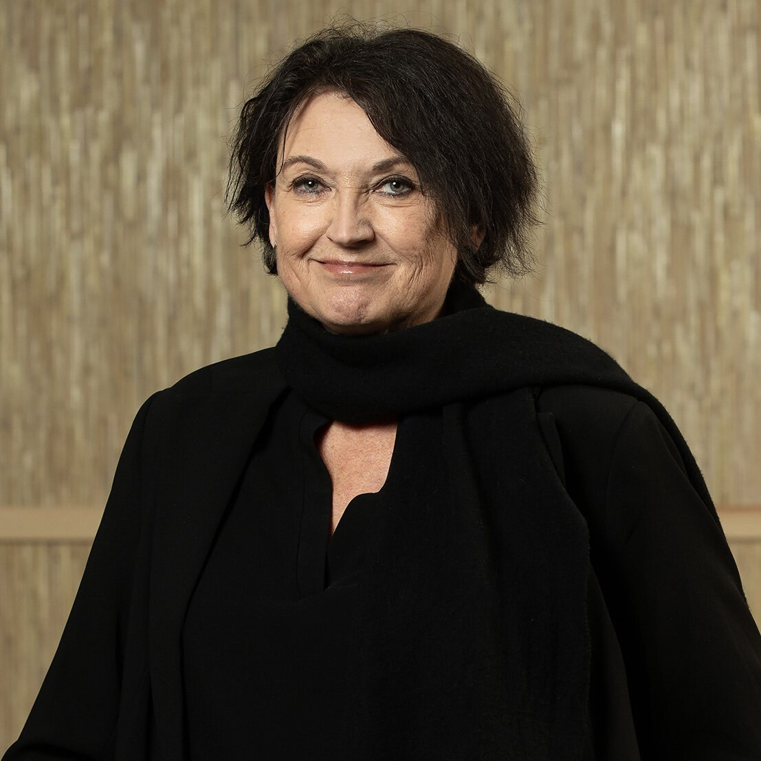 Foto av en smilende Bjørg med kort mørkt hår og sort bluse.