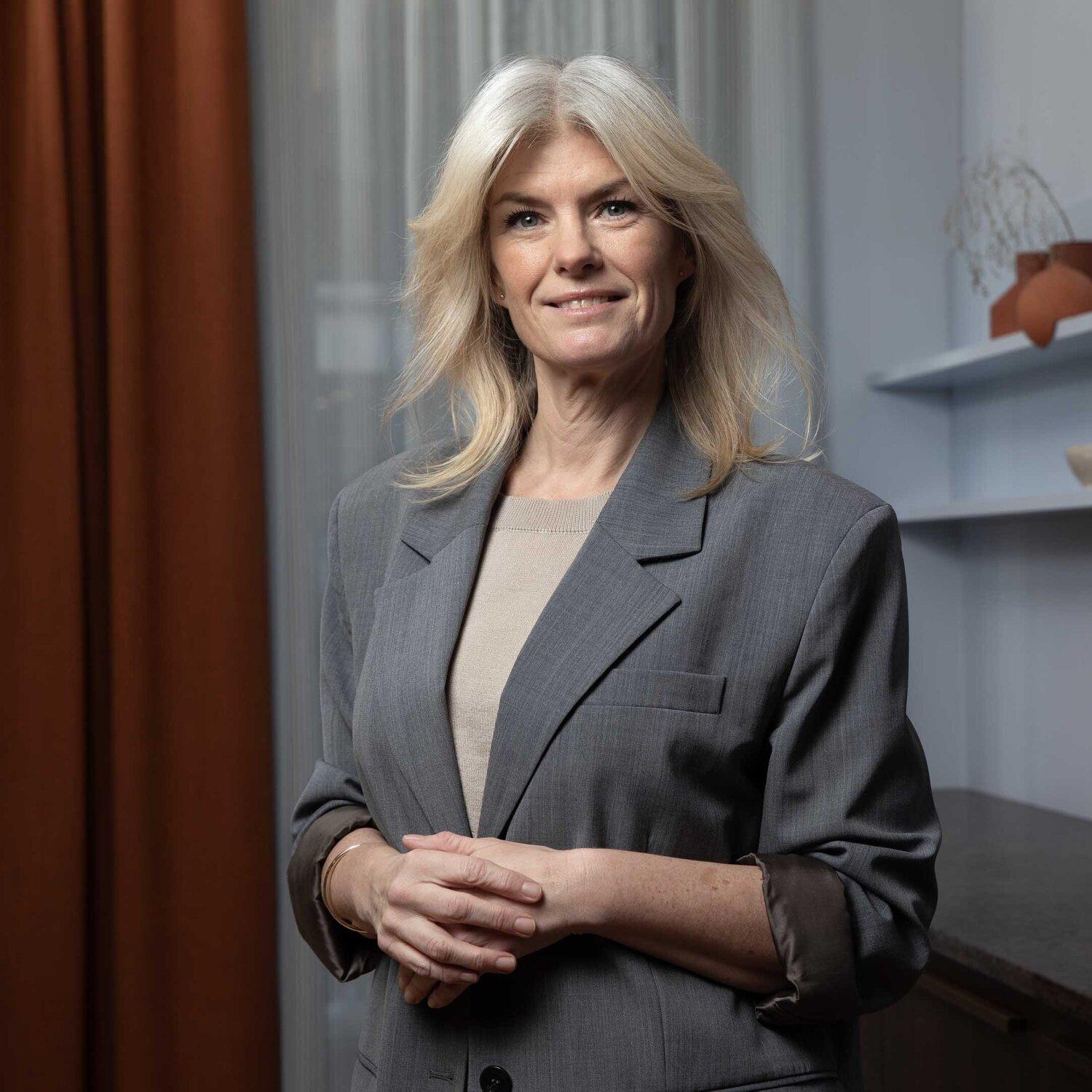 Foto av Cecilie som har halvlangt lyst hår og smiler mildt mot kamera med hendene i siden.