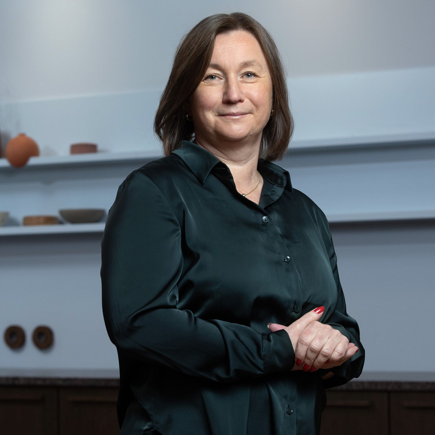 Foto av Hanne Cecilie med et vennlig smil og halvlangt, brunt hår. Hun har på seg en flaskegrønn silkeskjorte og har fine, rødmalte negler.