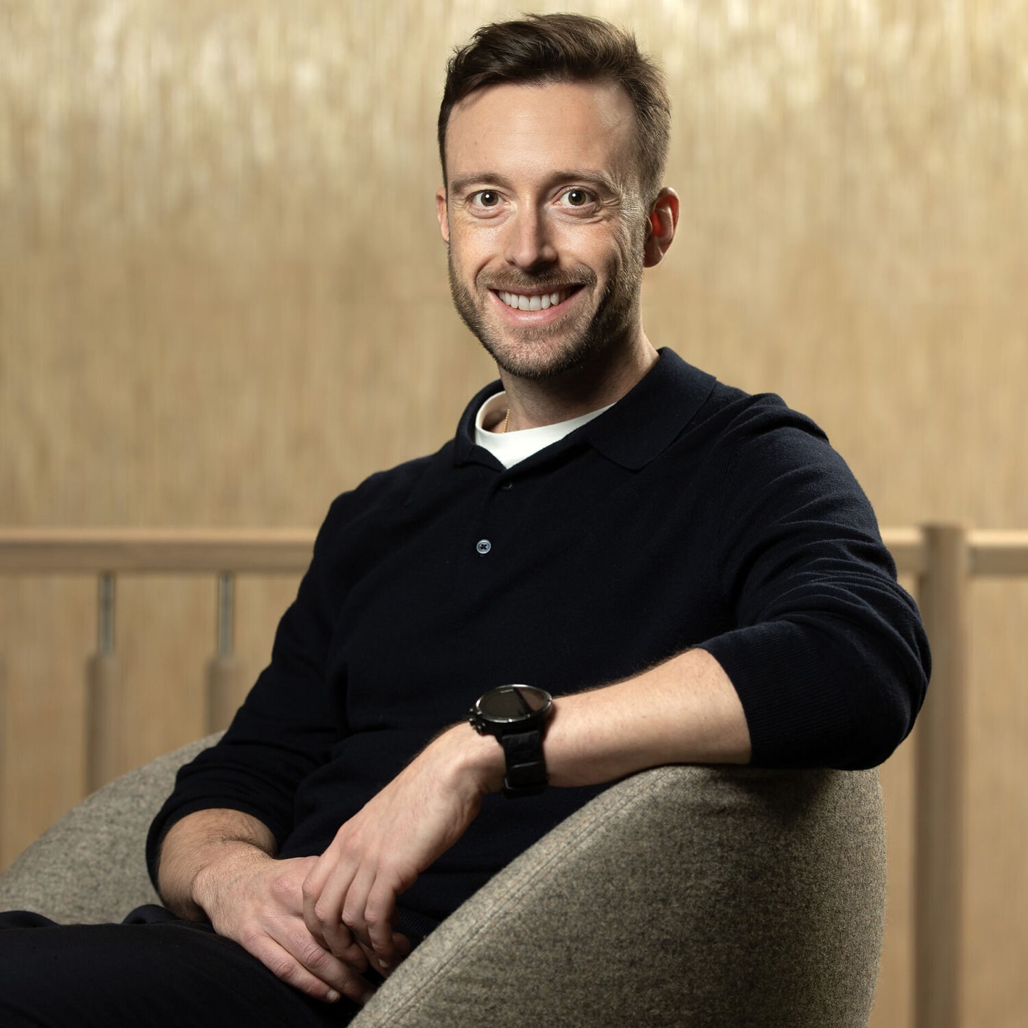 Foto av Kim-André som smiler inn i kameraet. Han har kortklipt, mørkt hår, og har på seg en sort piquet-skjorte med en hvit t-skjorte innenfor.