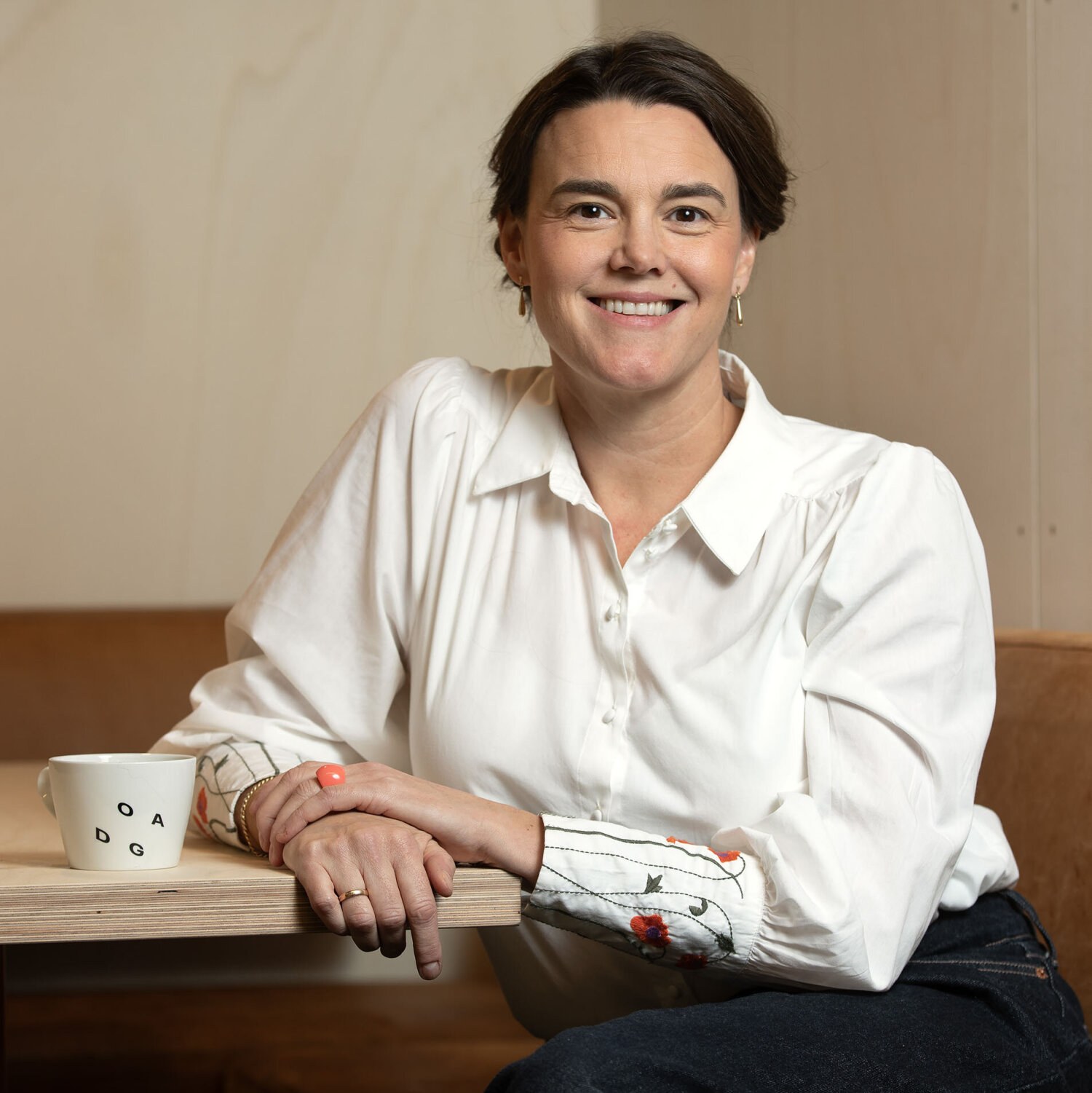 Foto av Sissel smiler med mørkt oppsatt hår og hvit bluse med broderier på mansjettene.