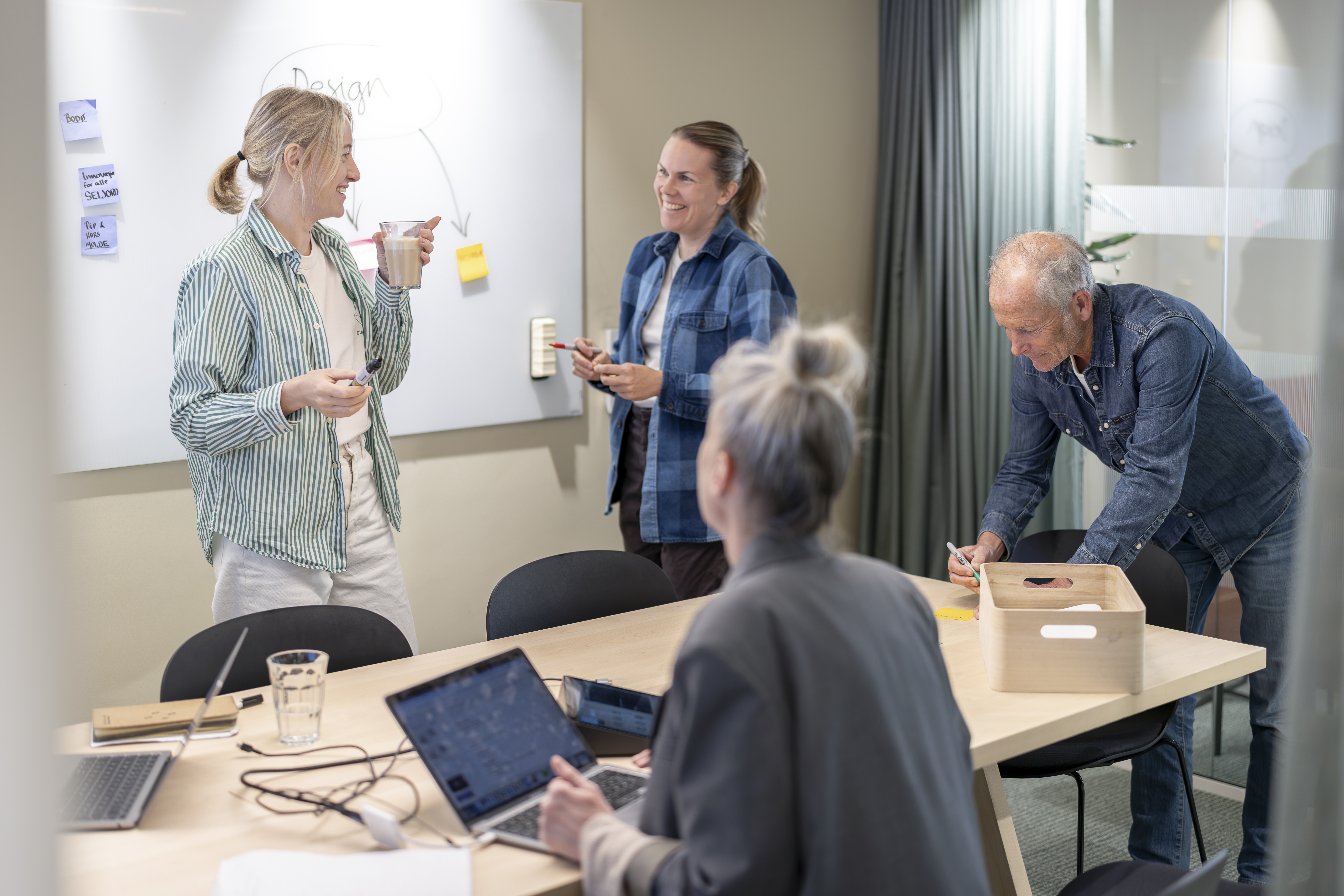 Foto av fire personer som jobber sammen i lystig lag på et møterom.