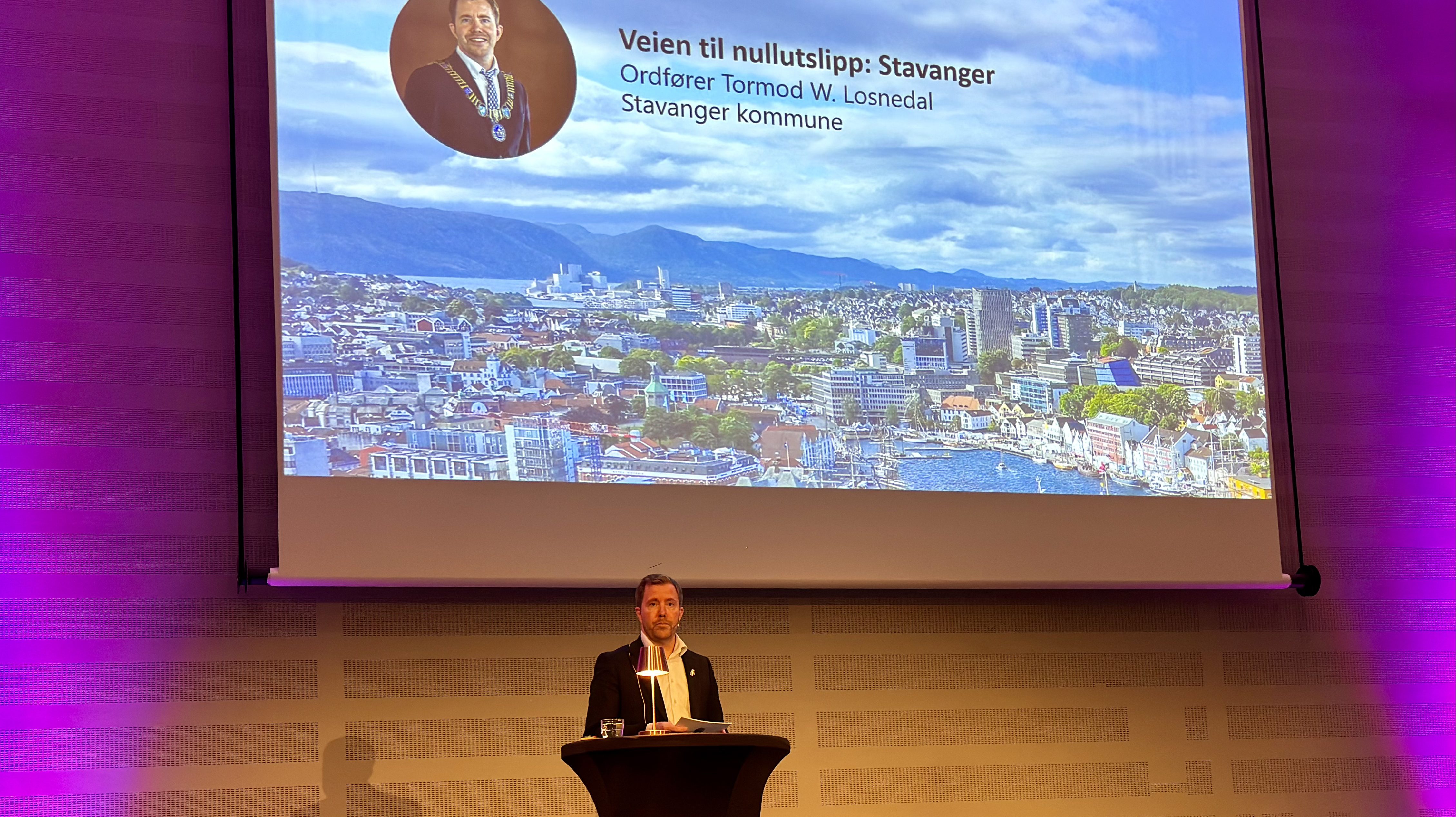 Ordføreren i Stavanger Tormod W. Losnedal står på talerstolen med en presentasjon med bilde av Stavanger i bakgrunnen.