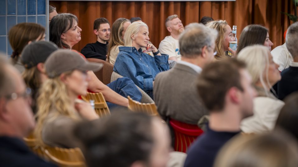 Foto av en samling mennesker som sitter og lytter til et foredrag.