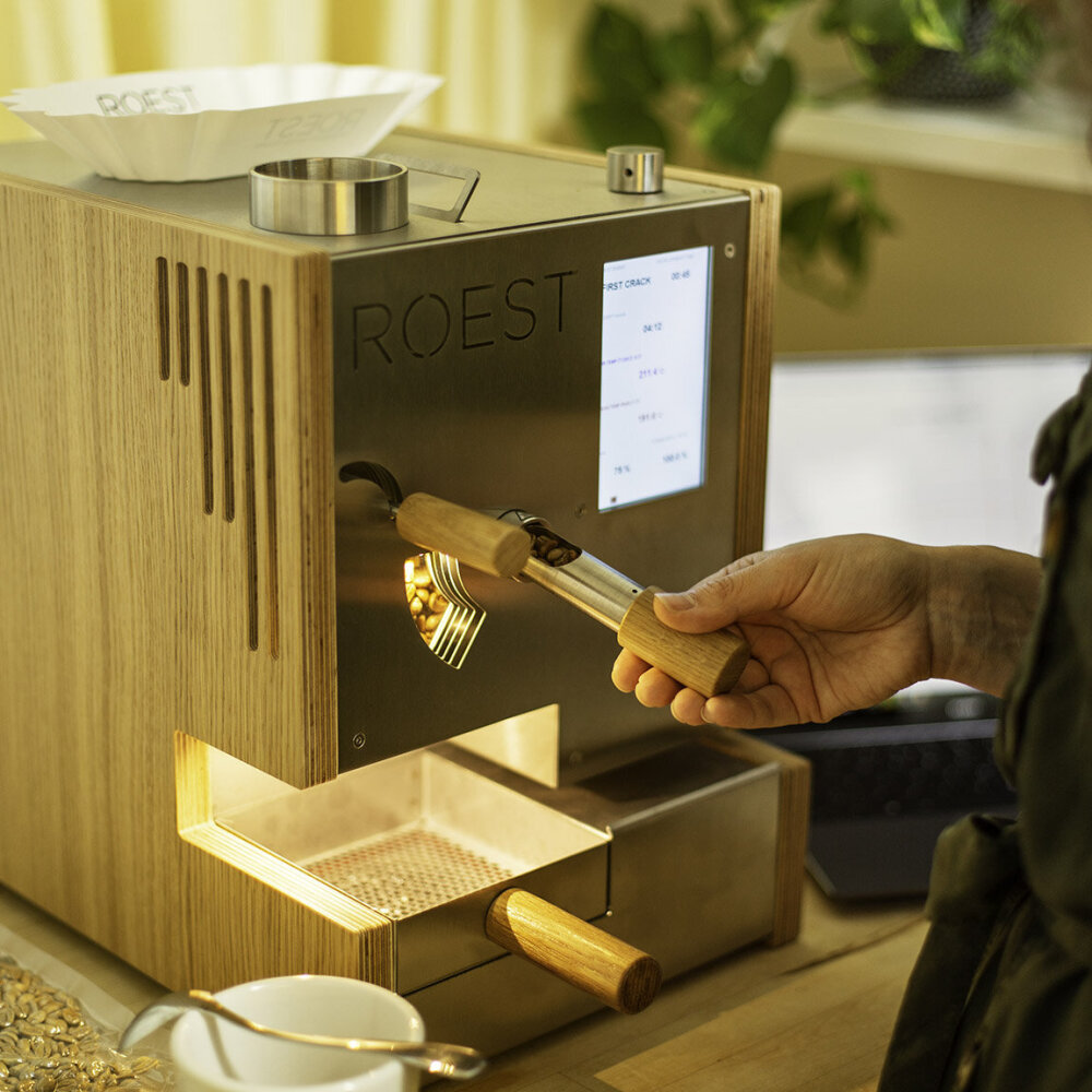 Foto av en hånd som holder på en spak på en kaffemaskin.