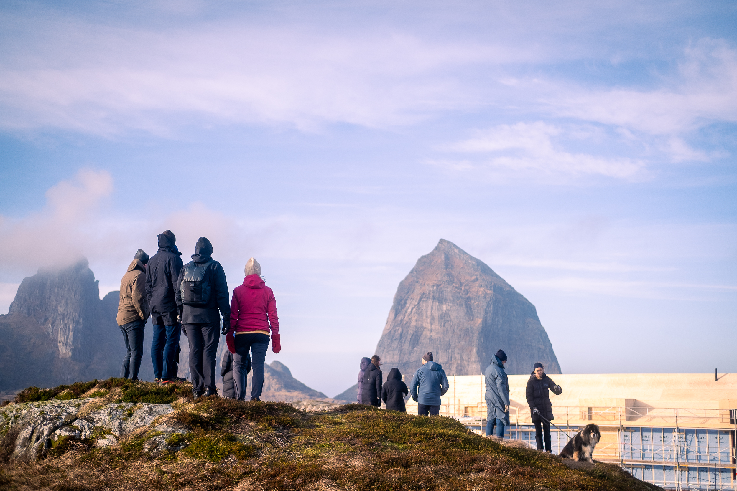 Mennesker i turklær fotografert bakfra mens de ser mot en stor fjelltopp.