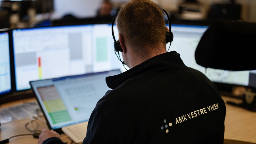 Bildet viser ryggen på en operatør på AMK-sentralen (113) som ser på flere skjermer.