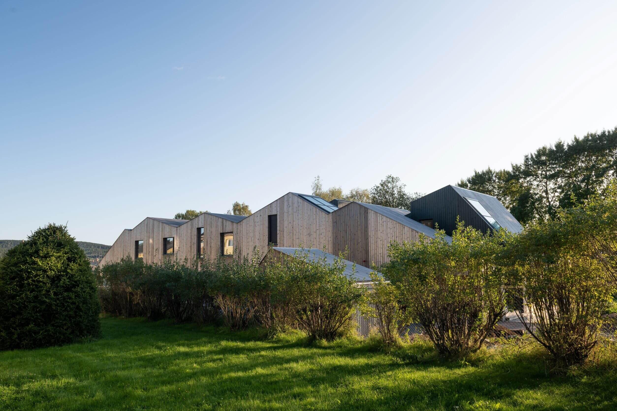Siluetten av et trehus mot blå himmel.