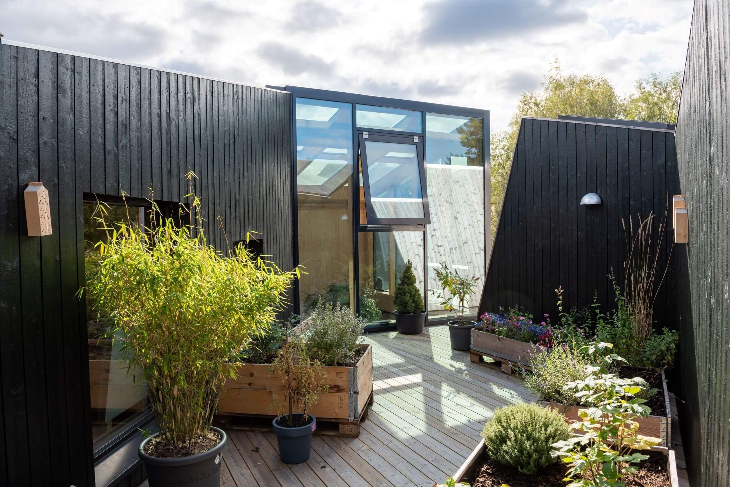 Utvendig fasade av trehus med planter.