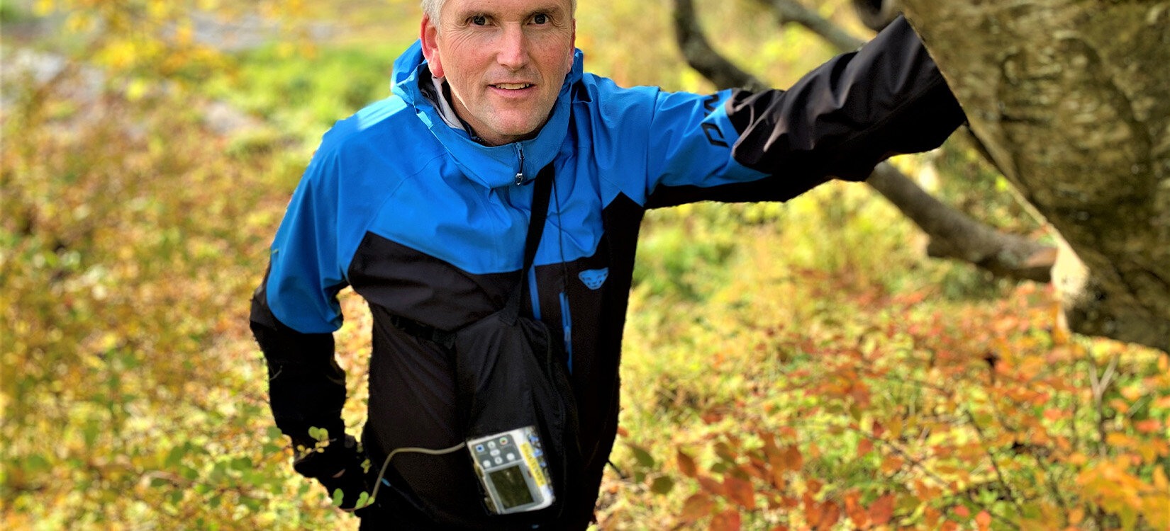 Bildet viser en mann som lener seg mot et tre. Rundt halsen har han en elektronisk pumpe som bruker til antibiotikabehandling.