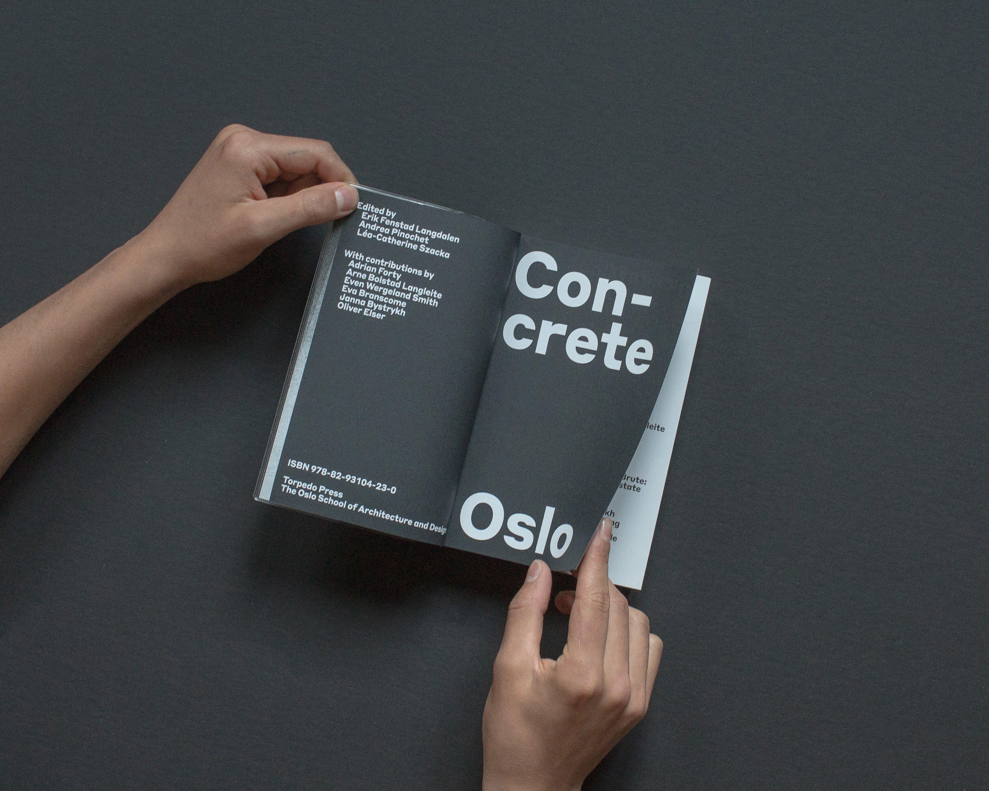 Hender som holder i hvert sitt hjørne av en oppslått bokside med tittel Naturbetong. Gråsvart bakgrunn