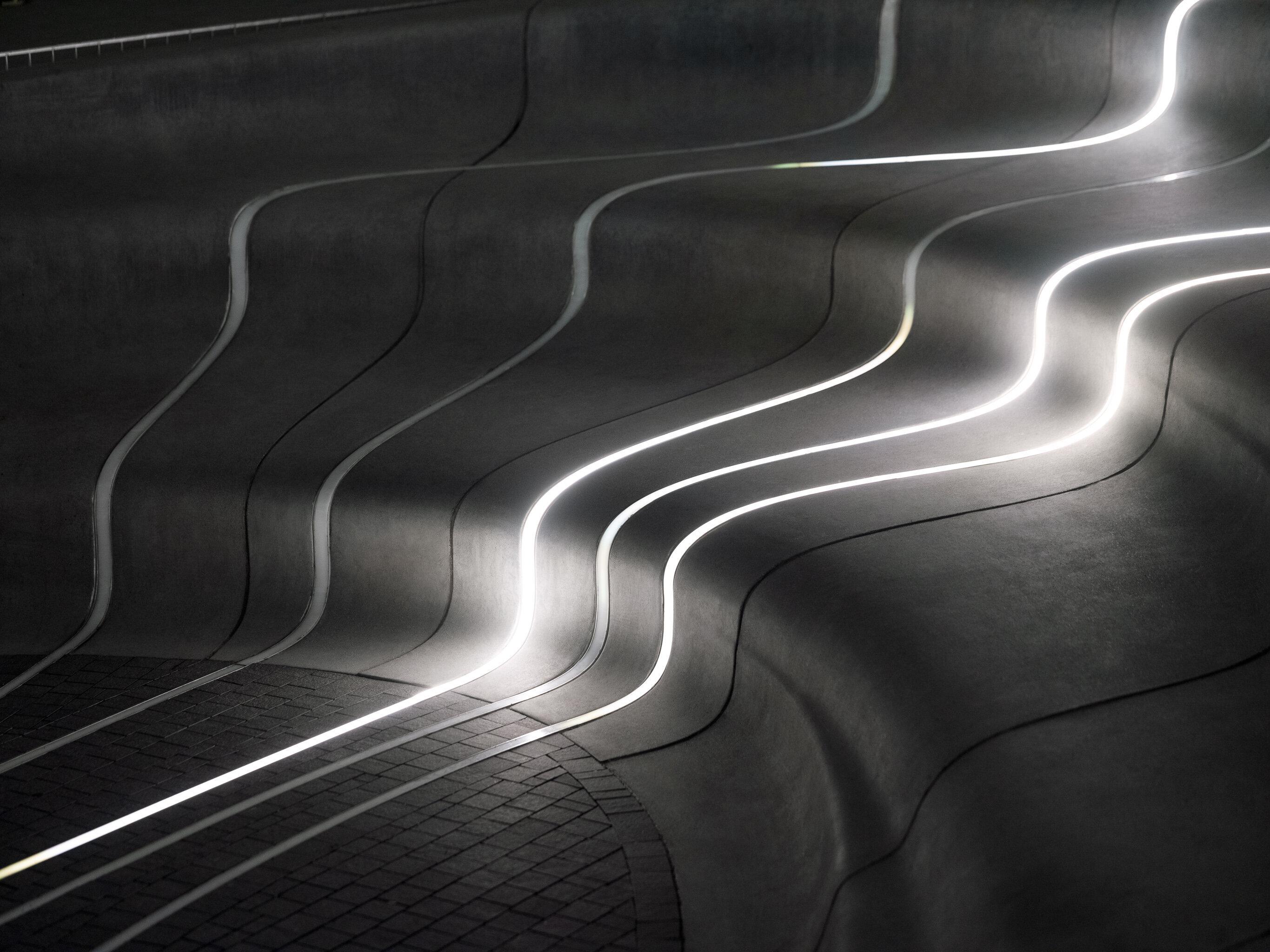 Bølgende former av lys ned en trapp med buede trinn.