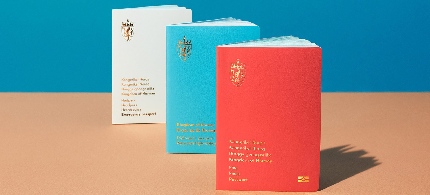 Tre varianter av det norske pass er oppstilt på et bord.