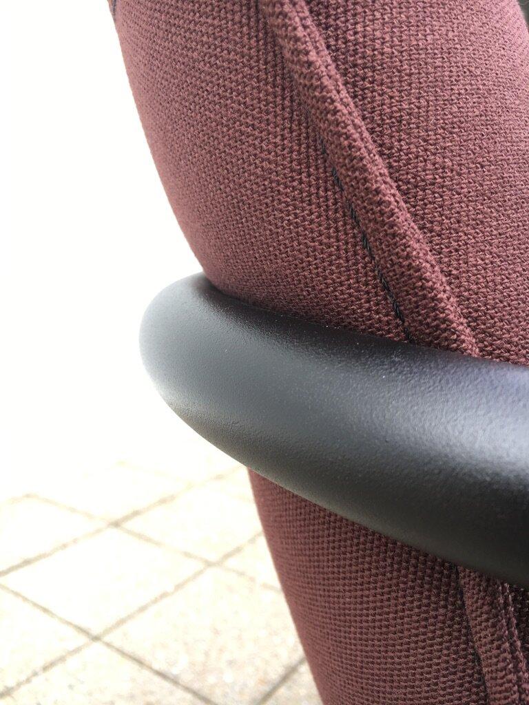 Et detaljfoto som viser hvordan armlenet svinger seg rundt ryggputen på stolen.