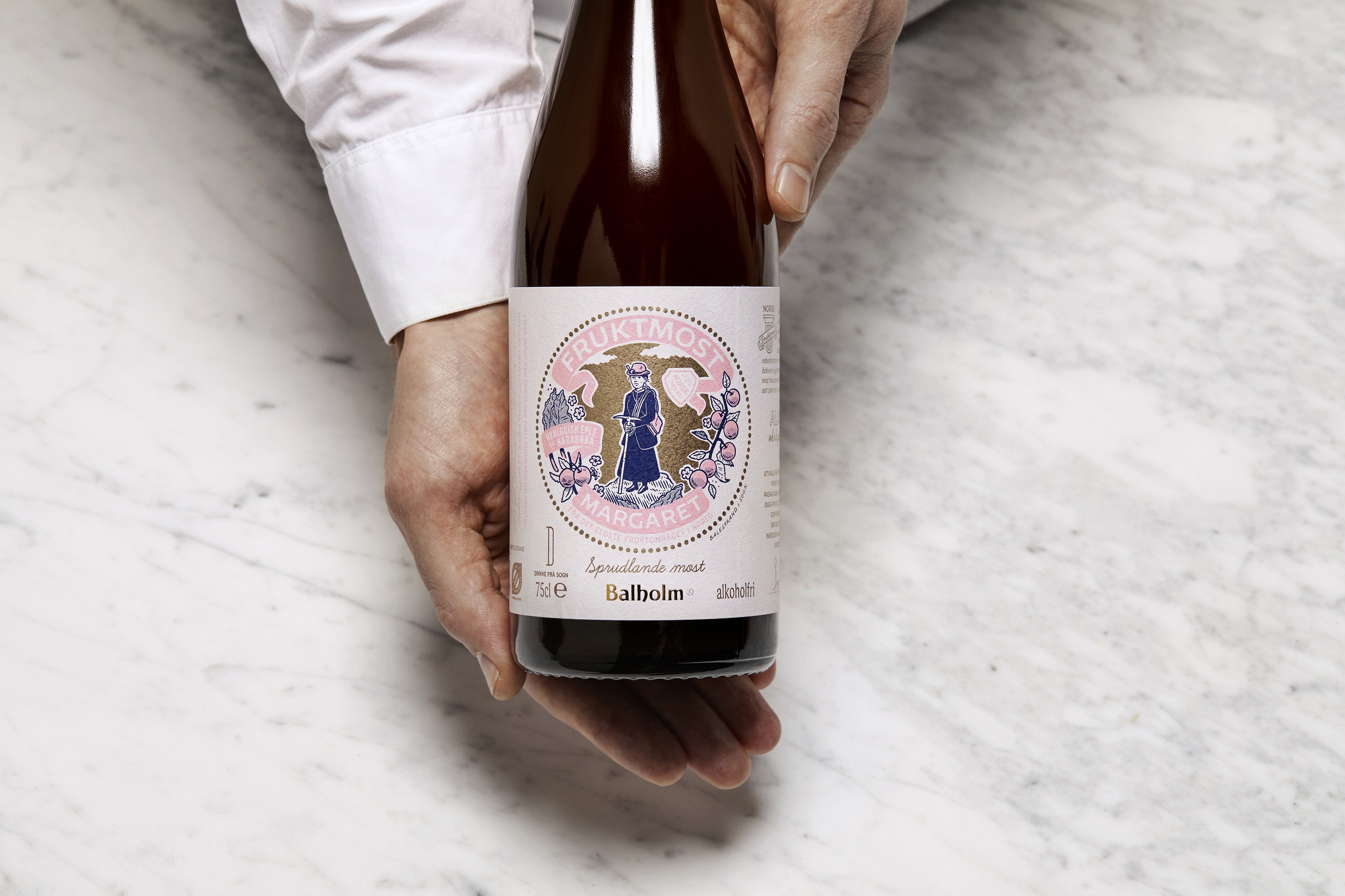 En person utenfor bildet holder rundt en flaske fruktvin