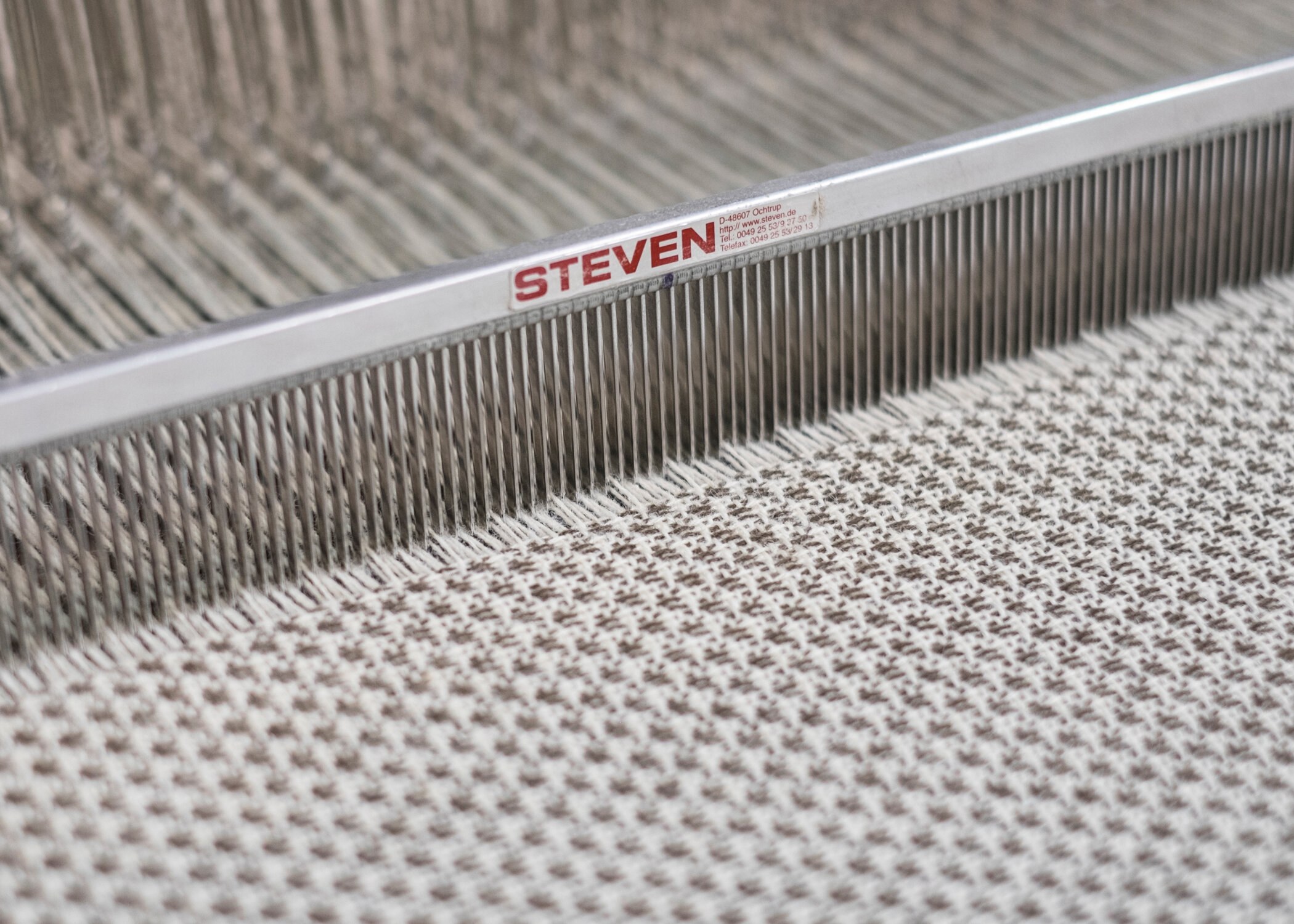 Et nærbilde av et lyst ullstoff i en maskinell vev.