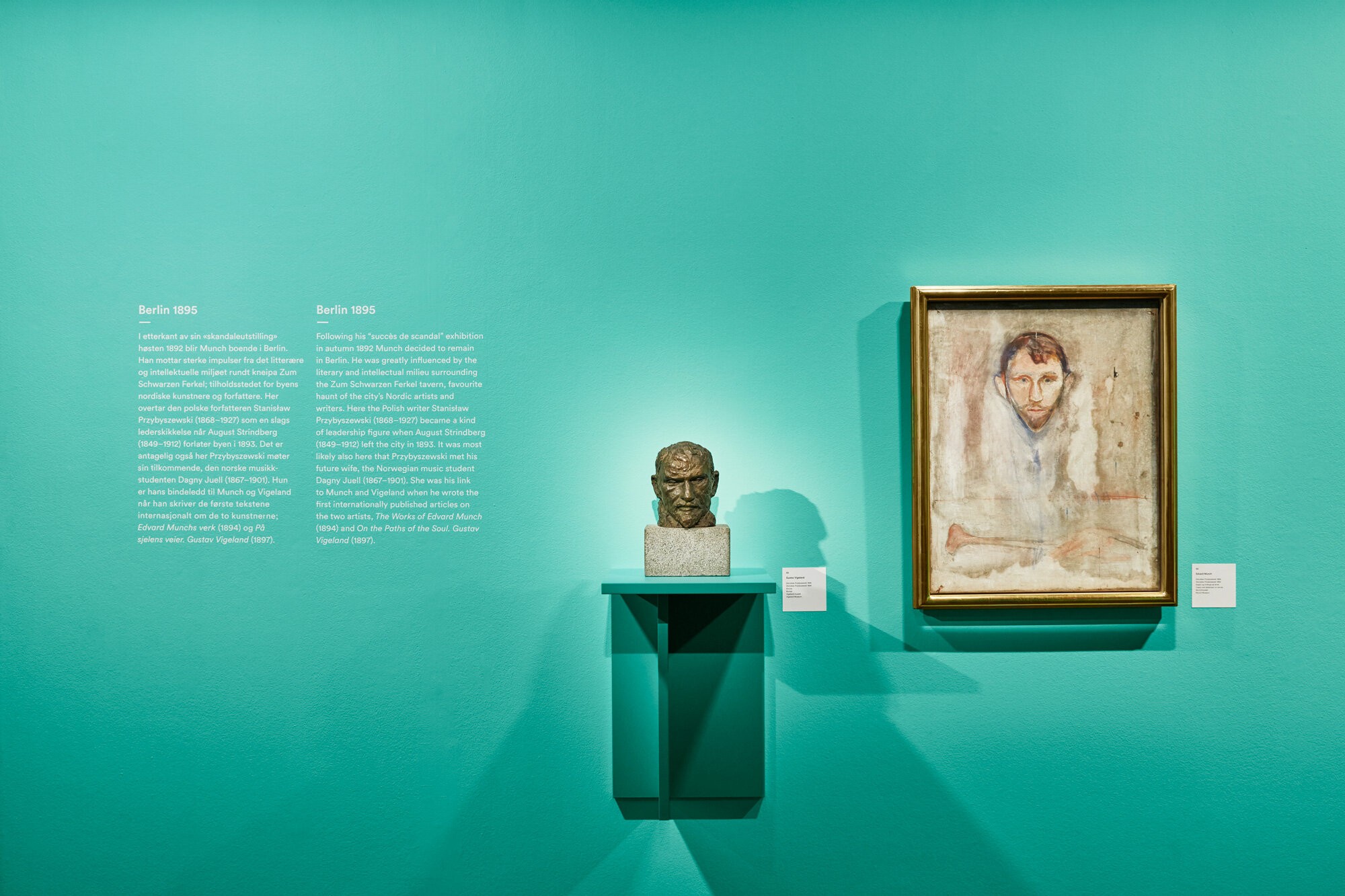 Bildet viser del av utstillingen Vigeland+Munch. En statue av et mannehode er plassert på en hylle, ved siden av et maleri an en mann der hode og ansikt er det mest fremtredende. Veggen og hyllen er malt i turkis.