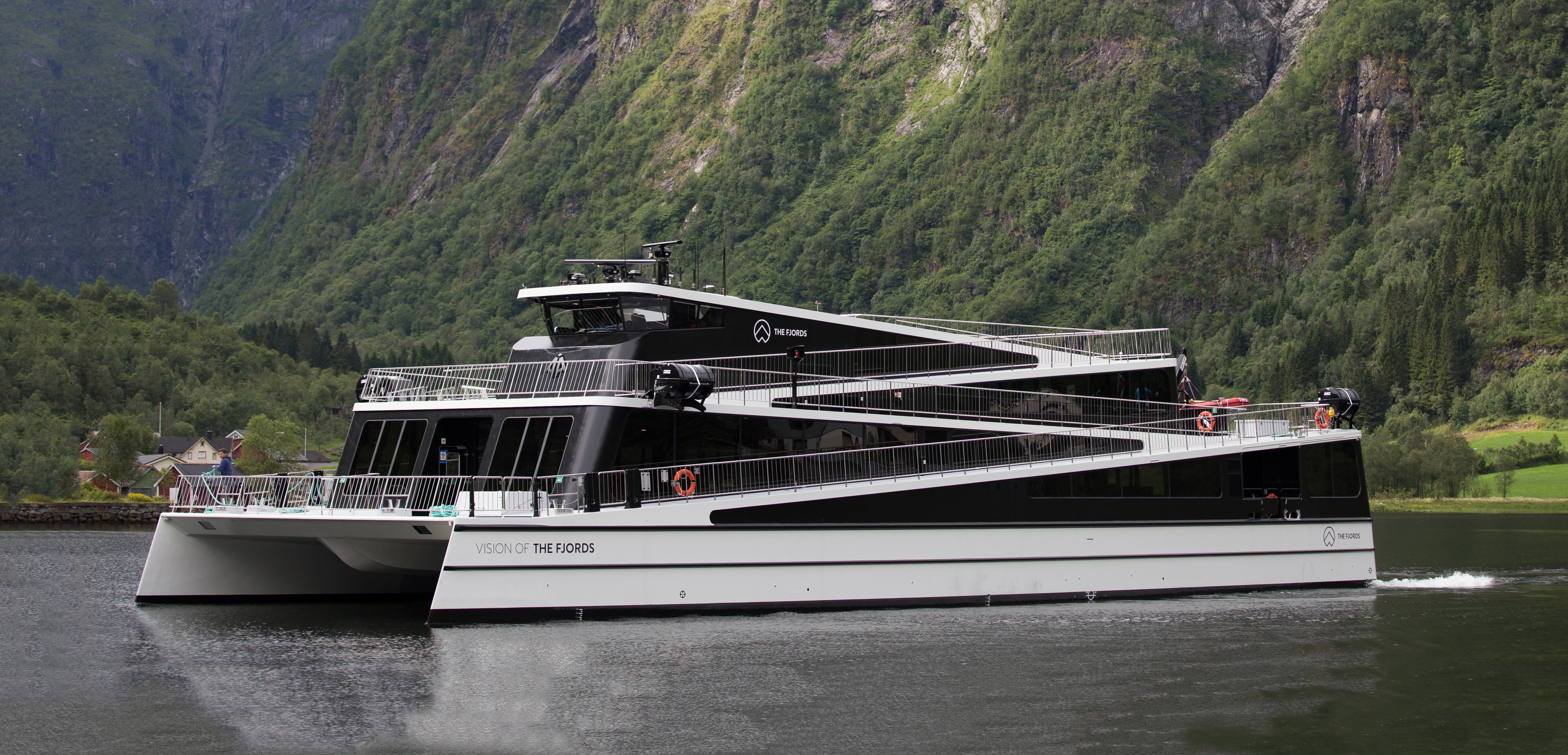 Et bilde av båten med ene langsiden vendt mot kamera. Båten har tre etasjer og en trappefri gangvei som gir adkomst fra første plan og opp til toppen av styrehuset.