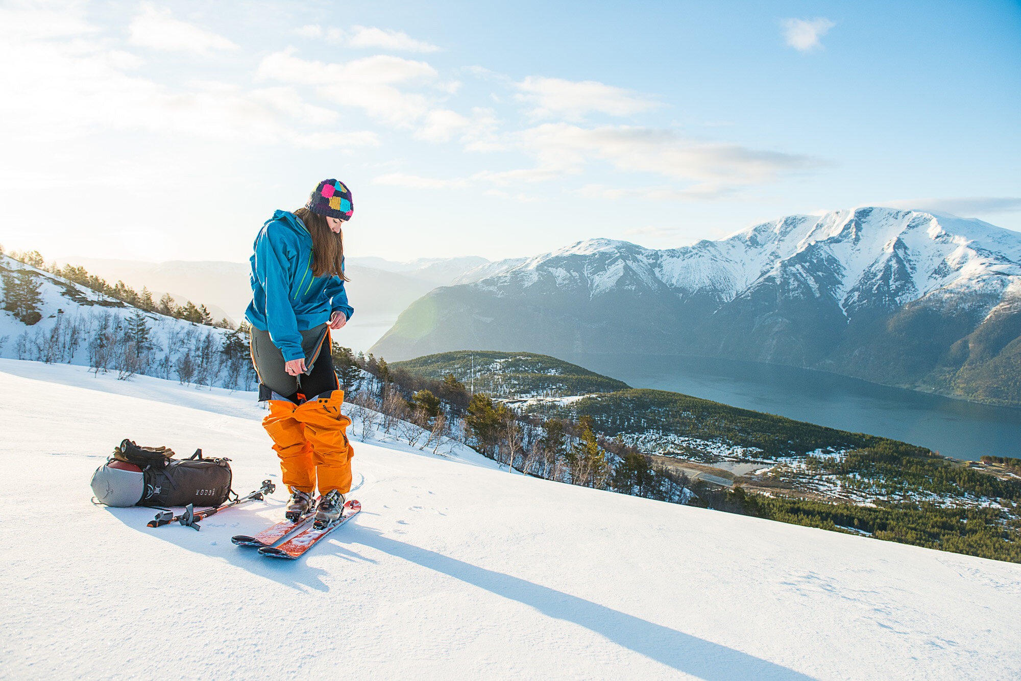En kvinne på alpintski har trukket ned alpintbuksen og drar i en glidelås på et par shorts hun har under.