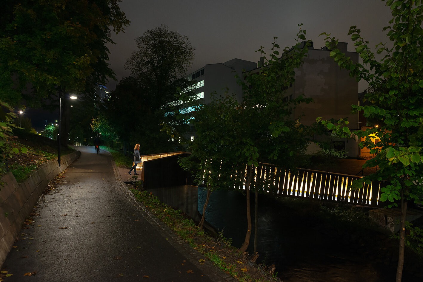 Illustrasjonsbilde av Elgsletta bro er om kvelden, med lys i rekkverket – sett fra gangveien på østbredden av Akerselva