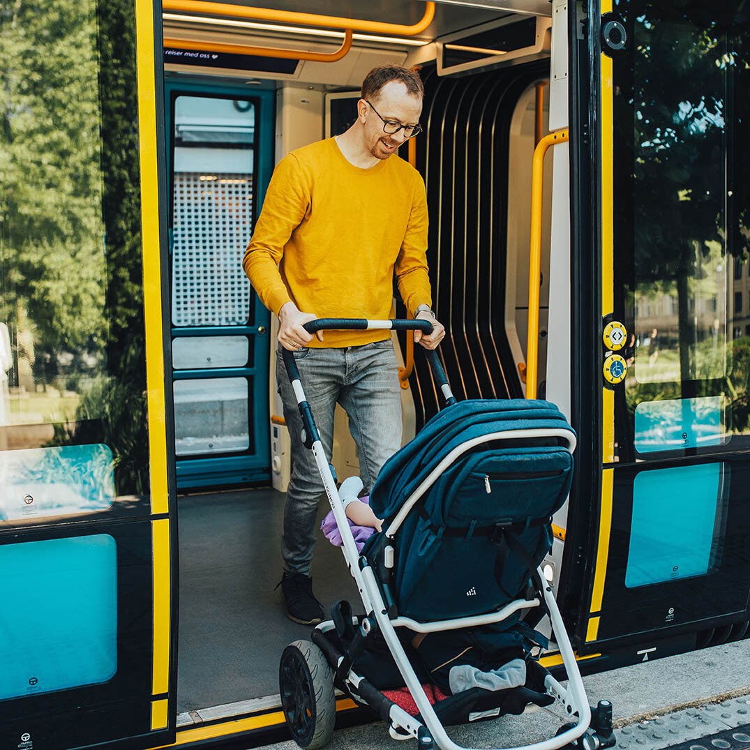 Far med vogn på vei ut av trikk.