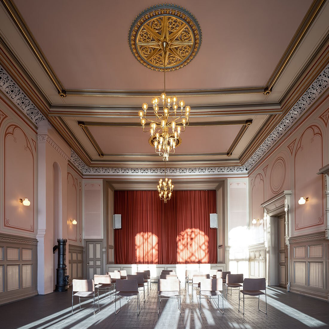 En herskapelig teatersal med nyrestaurerte rosetter, lysekroner og ornamenter.