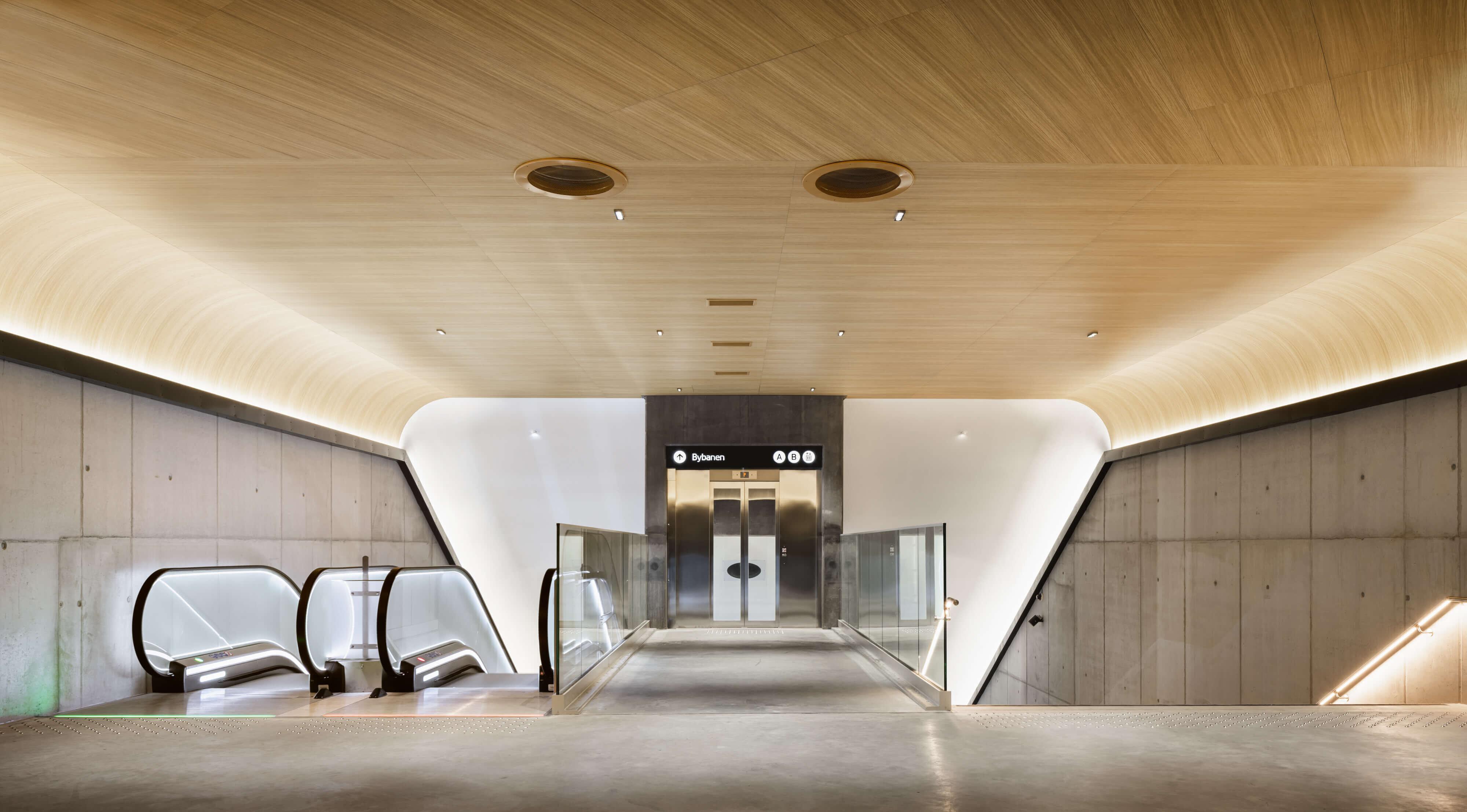 Åpent og lyst inngangsparti med rulletrapp, heis og trappeløp.