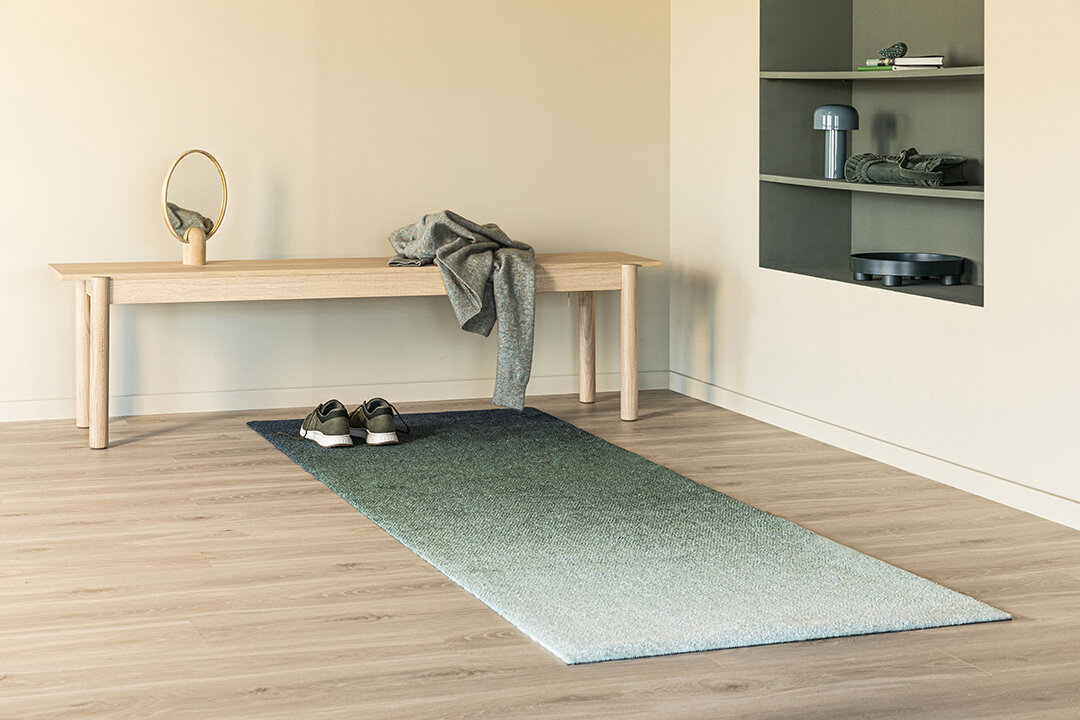 Interiør av lys gang med grønntonet teppe på gulvet.