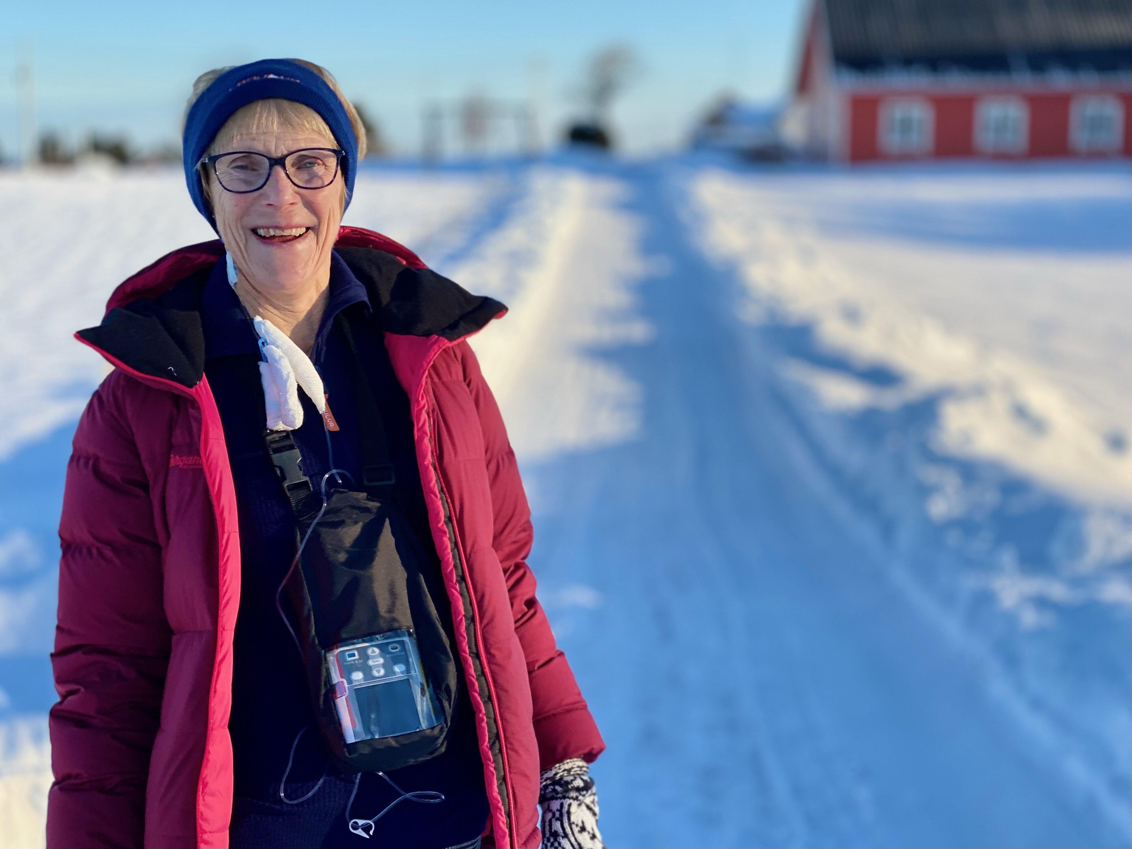 Person står ute på en snødekt vei med bærbar medisinsk pumpe for antibiotikabehandling rundt halsen.
