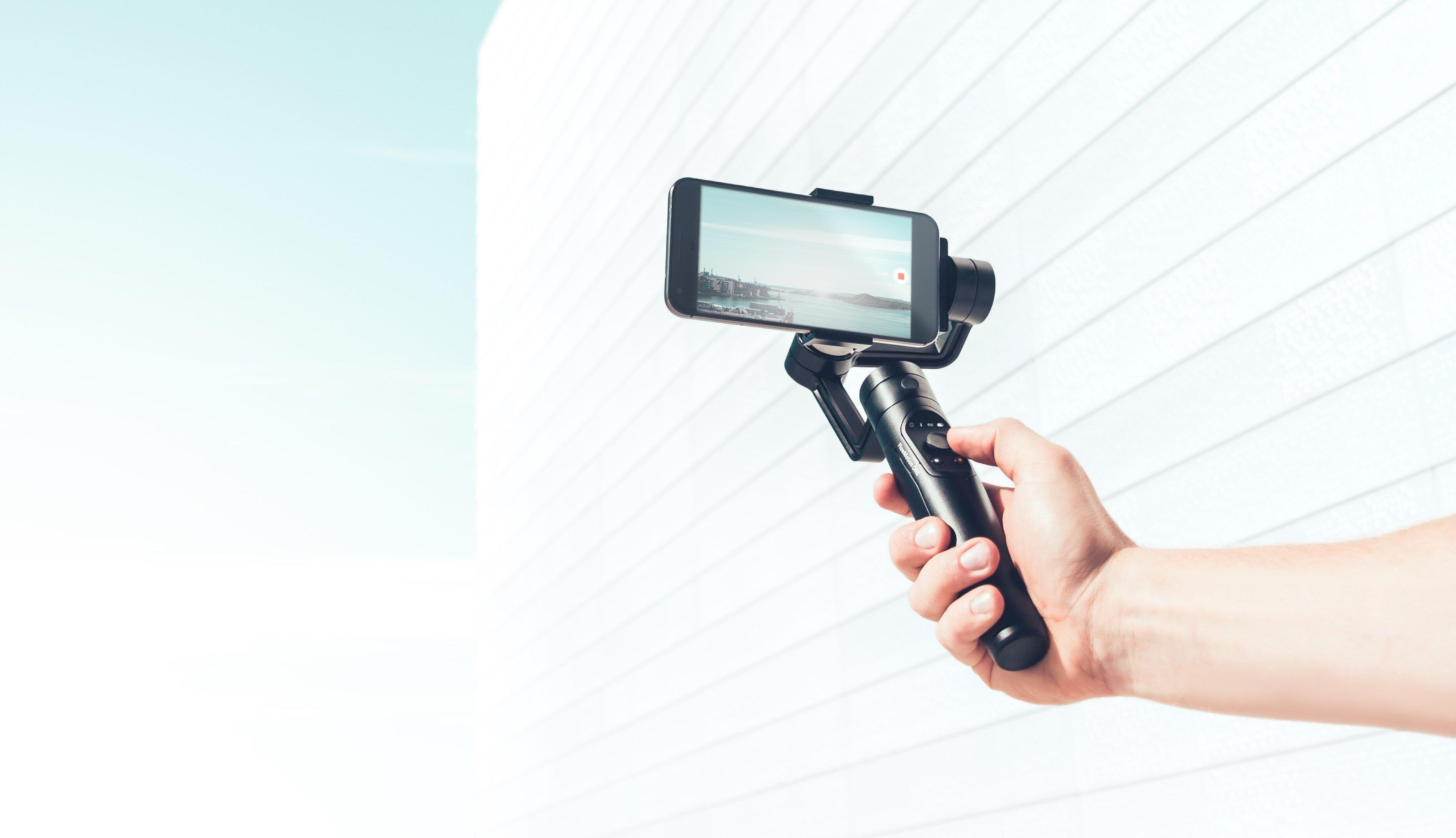 En hånd holder opp et stativ med en smarttelefon koblet til.