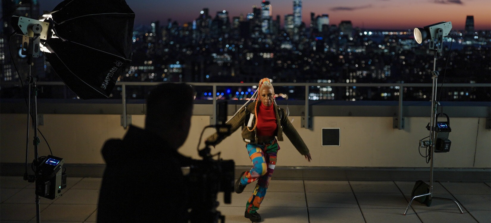 Filmlampa Kelvin Etos 300 i bruk på sett. En artist danser på taket av en bygning foran Manhattan skyline.