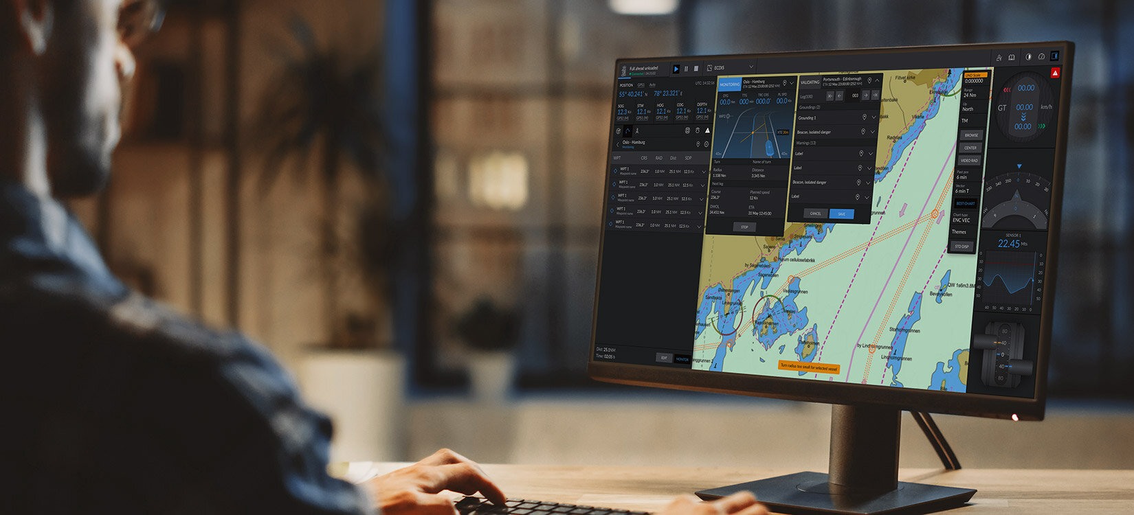 En mann arbeider på en pc – på skjermen ser vi kart og flere programvinduer med ikke lesbar informasjon.