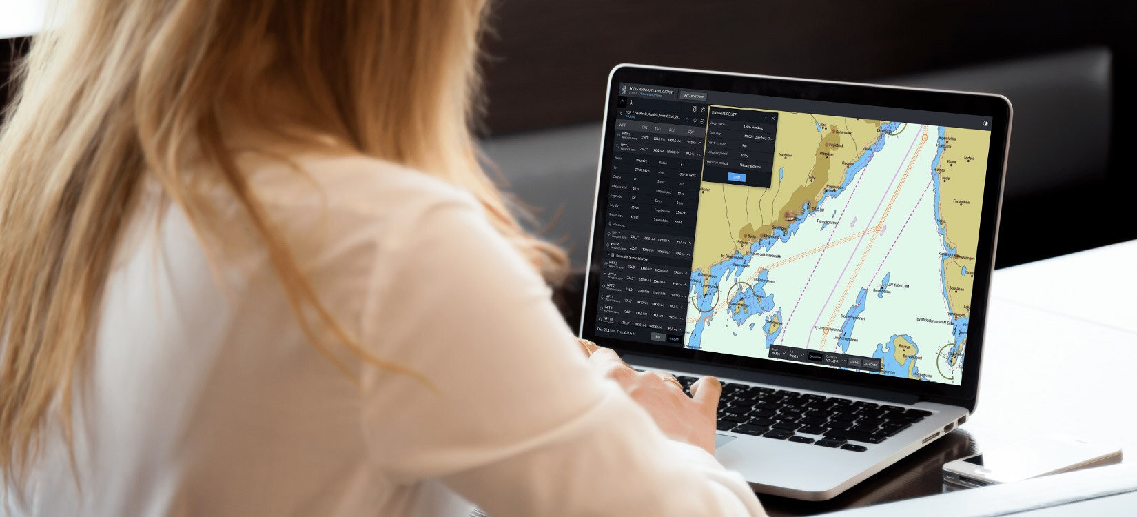 En kvinne arbeider på en laptop. Skjermen viser et kart med detaljert informasjon.